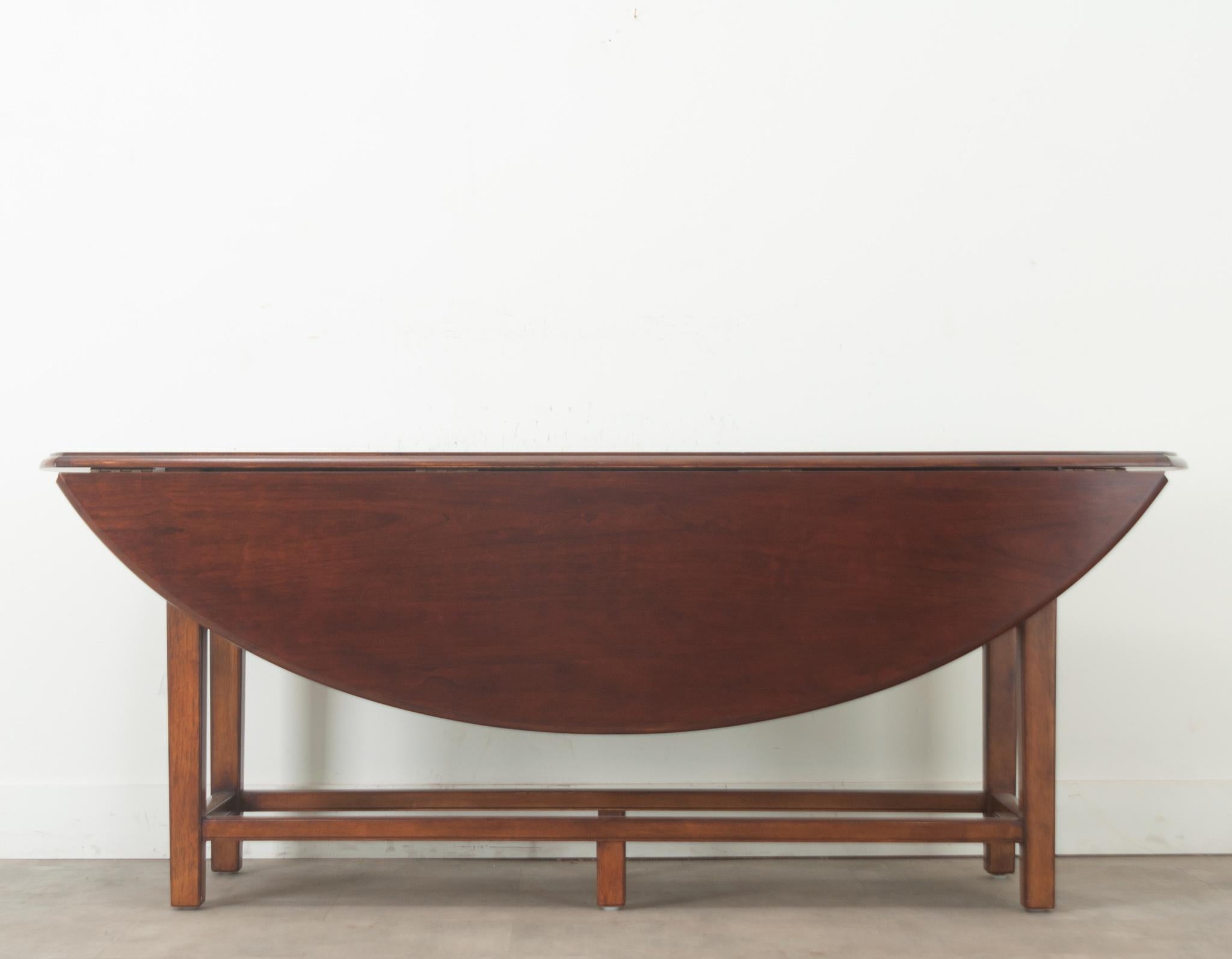 An English drop leaf dining table made of solid mahogany. This versatile dining table can be used as a console or a dining table. Four legs are connected with a sturdy stretcher adding support to this classic dining table. The drop leaves are
