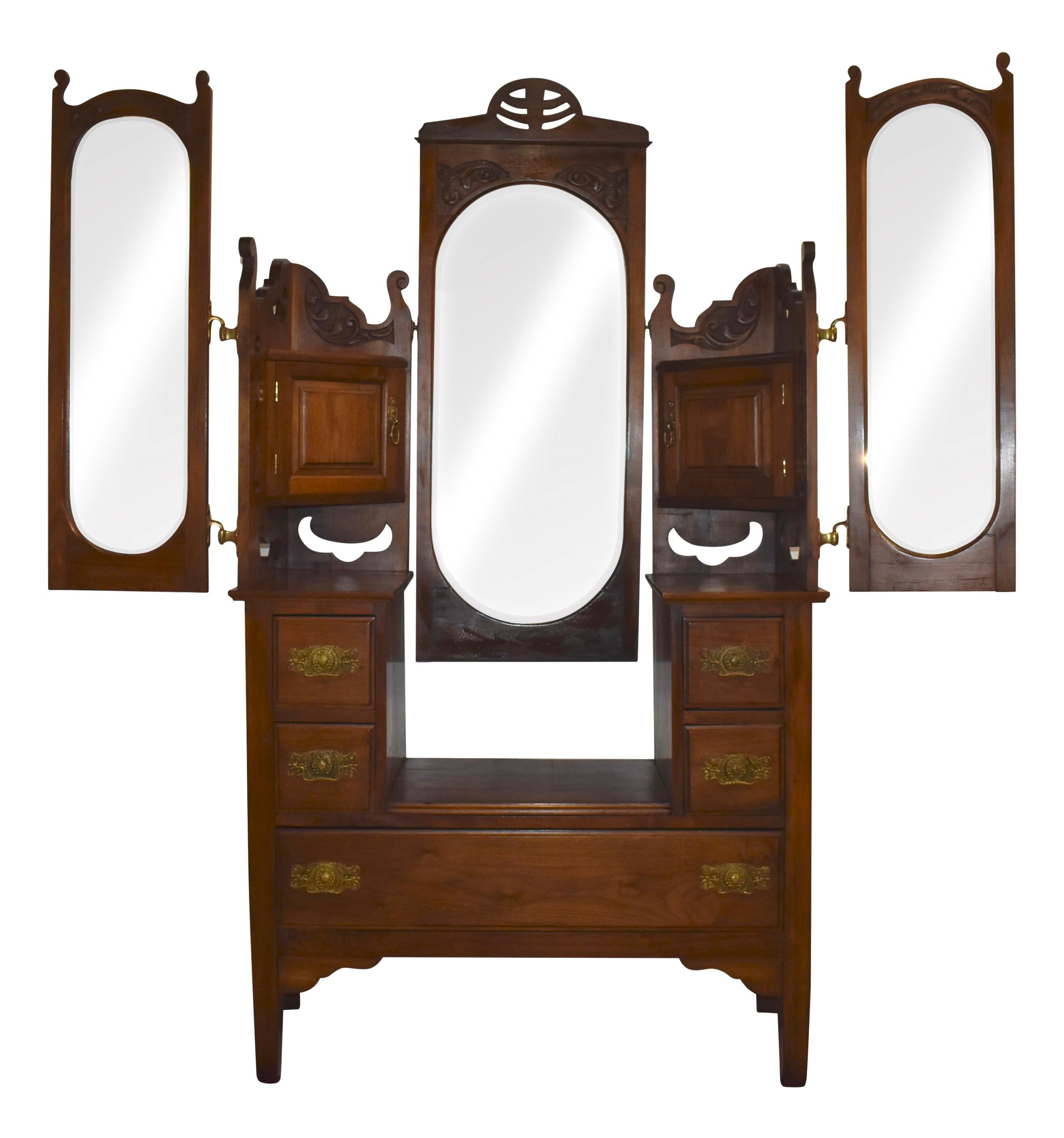 This stately, Edwardian dresser from the late 19th century features adjustable beveled mirrors and generous storage. A drop-center flanked by two small drawers on each side over a wide lower drawer creates space for a pivoting oval mirror in a