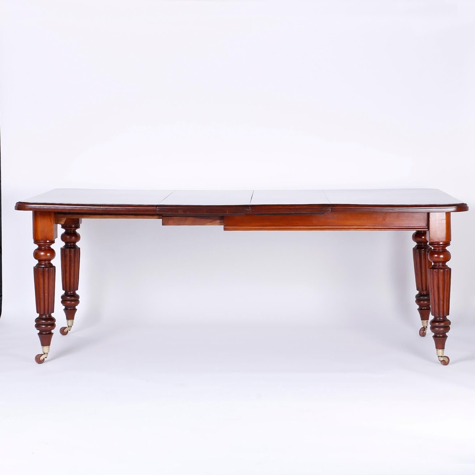 English late Regency, William IV extendable dining table crafted in mahogany with Classic form and perfect proportions. The top is well grained and beveled with two leaves and a crank to open and close. The legs are turned and beaded on brass