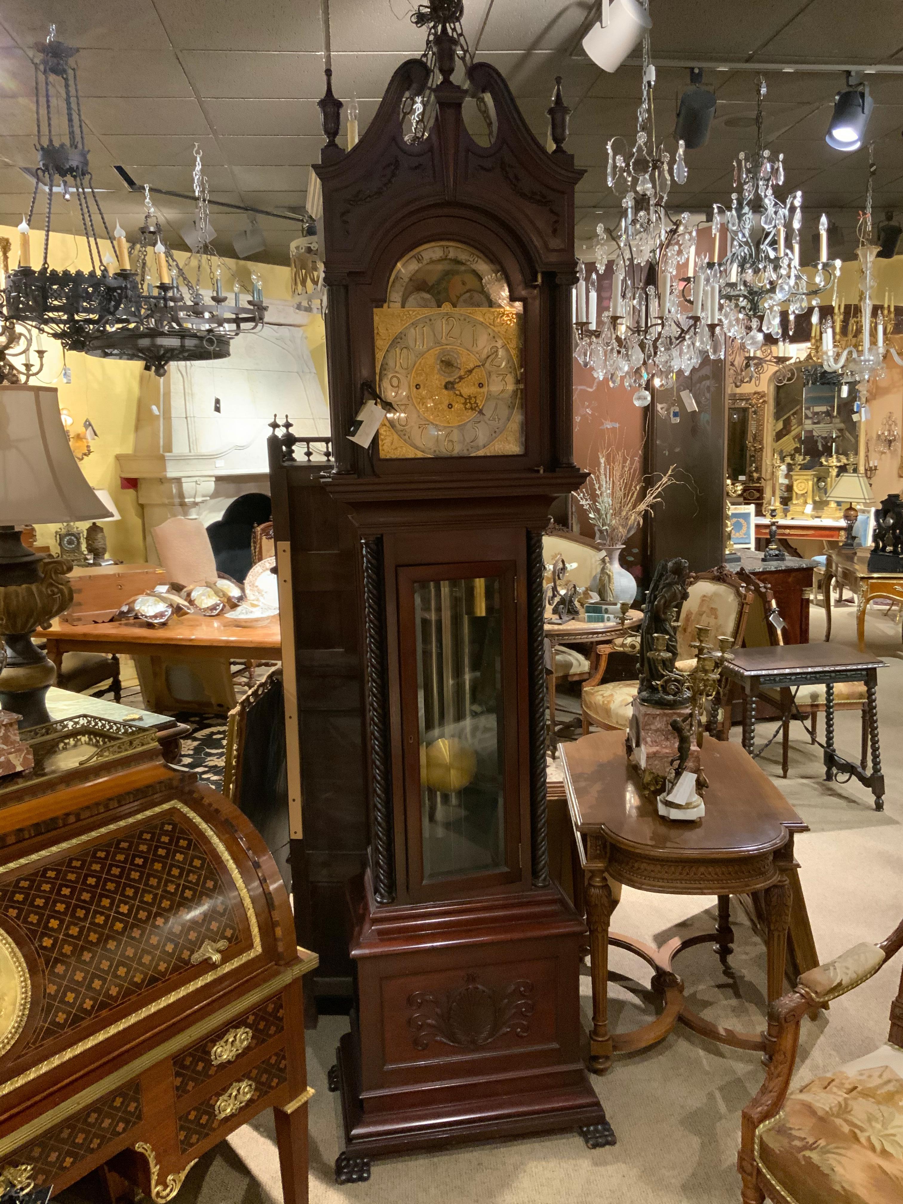 Mahogany long case clock with barley twist carved wood columns on each
side. Exquisite face in bronze dore with moon dial above. Arched pediment
with finials decorate the crest. It is in good working condition and has the
original key. It is
