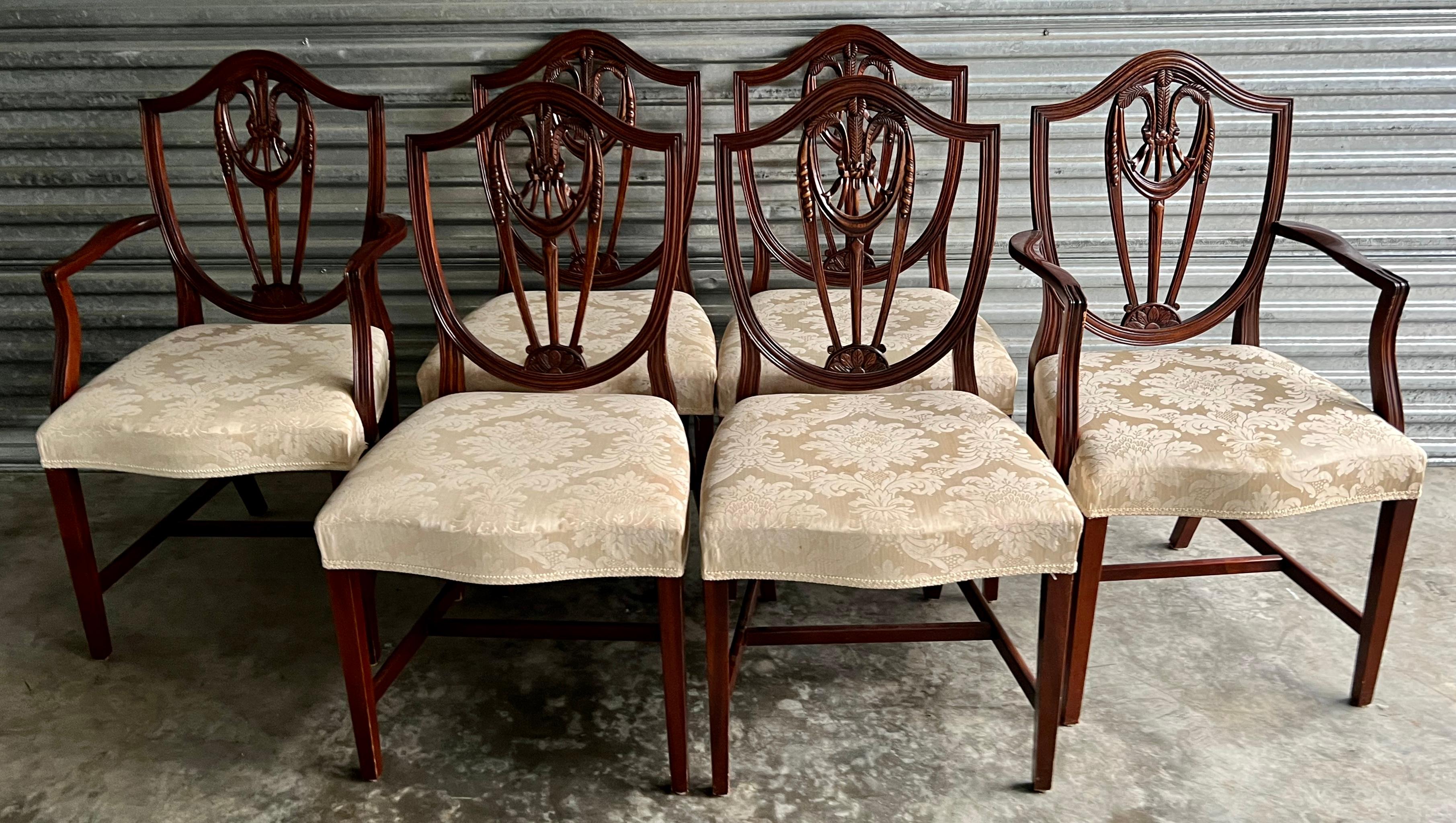 This is a set of mid-century English carved mahogany Hepplewhite style dining chairs by Bevan Funnell Ltd. The damask upholstery is vintage and does show some where. Measures: Arm; 22” L x 23” W x 38.5” H. Arm; 27” H.