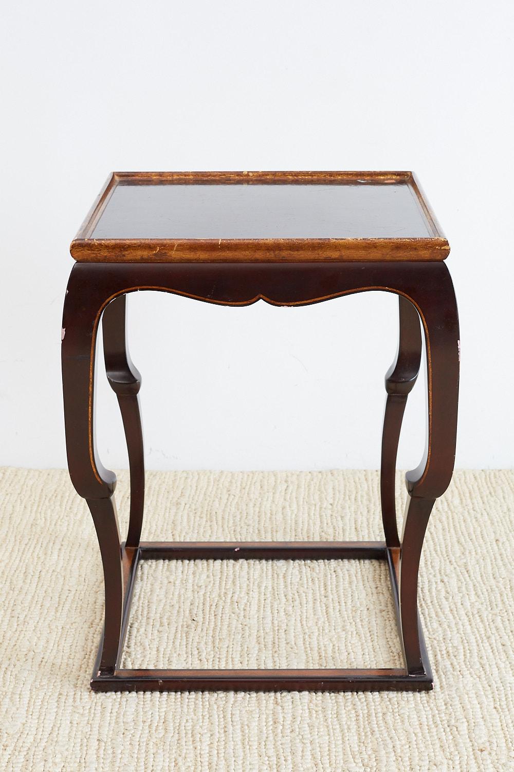 Distinctive English mahogany lacquered tavern table or drink table featuring a square cube form. The galleried top is accented by gilt trim as is the box stretcher on the bottom. The top is supported by unique legs that look like a cabriole leg on