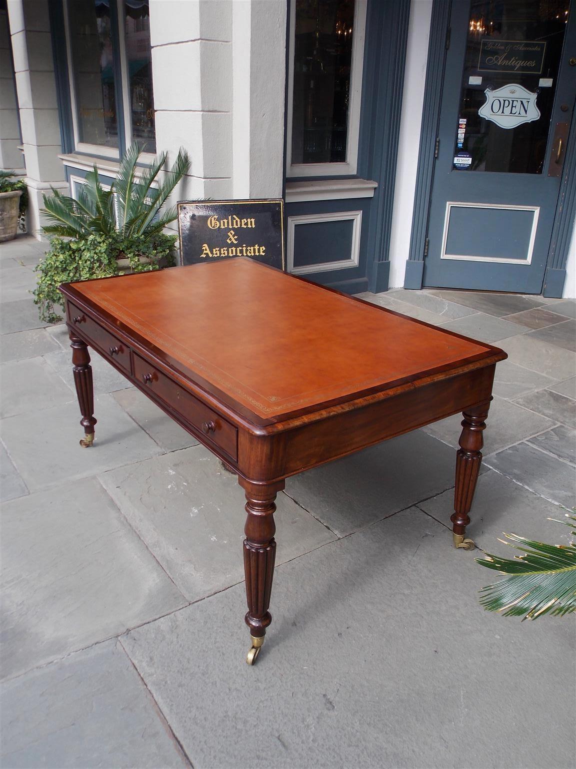 English mahogany leather top partners desk with a carved molded edge, four interior drawers with the original wooden knobs, and resting on turned bulbous reeded legs with the original brass casters, Early 19th century
23.5 tall knee height.