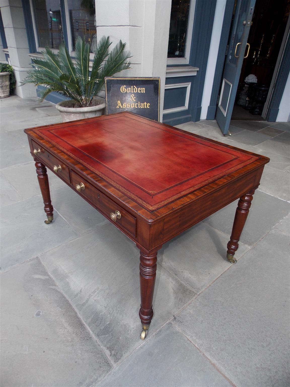 English mahogany leather top partners / writing desk with four flanking exterior drawers, original circular lion head brasses, and resting on turned bulbous ringed legs with the original brass cupped casters. Early 19th Century
Skirt height is 23.75