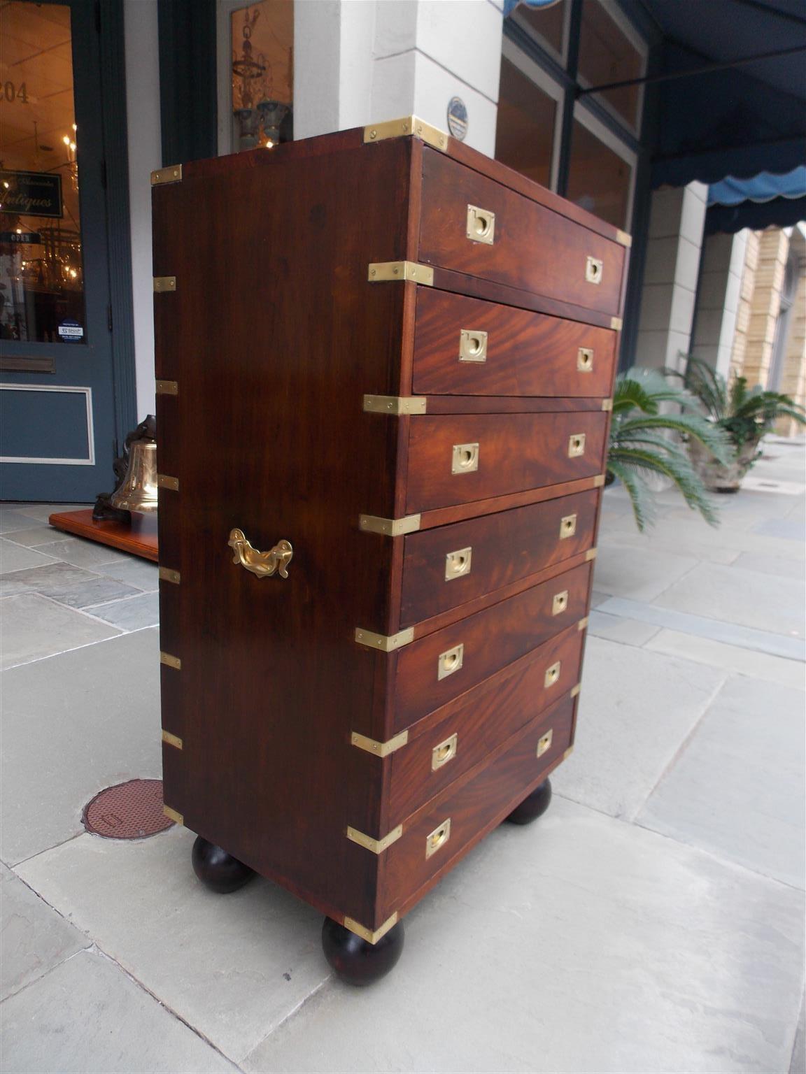 English mahogany military campaign seven drawer tall chest with original brass side handles, brass mounts, recessed brasses, and resting on the original bun feet, Late 19th century.