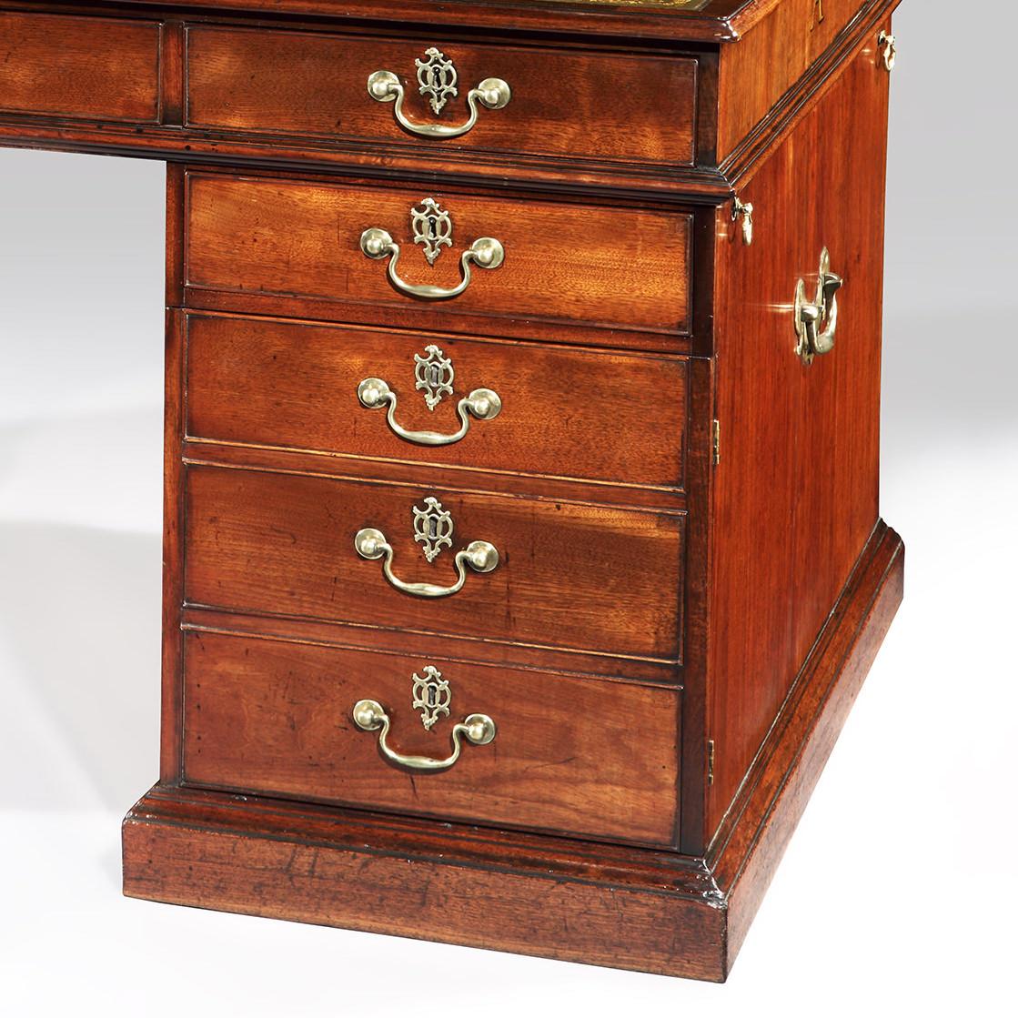 Constructed in a well patinated San Domingo mahogany of rectangular form, rising from a plinth base, the pedestals with laterally opposed banks of four oak lined lockable drawers, fitted with internal dividers and dressed with swan neck brass