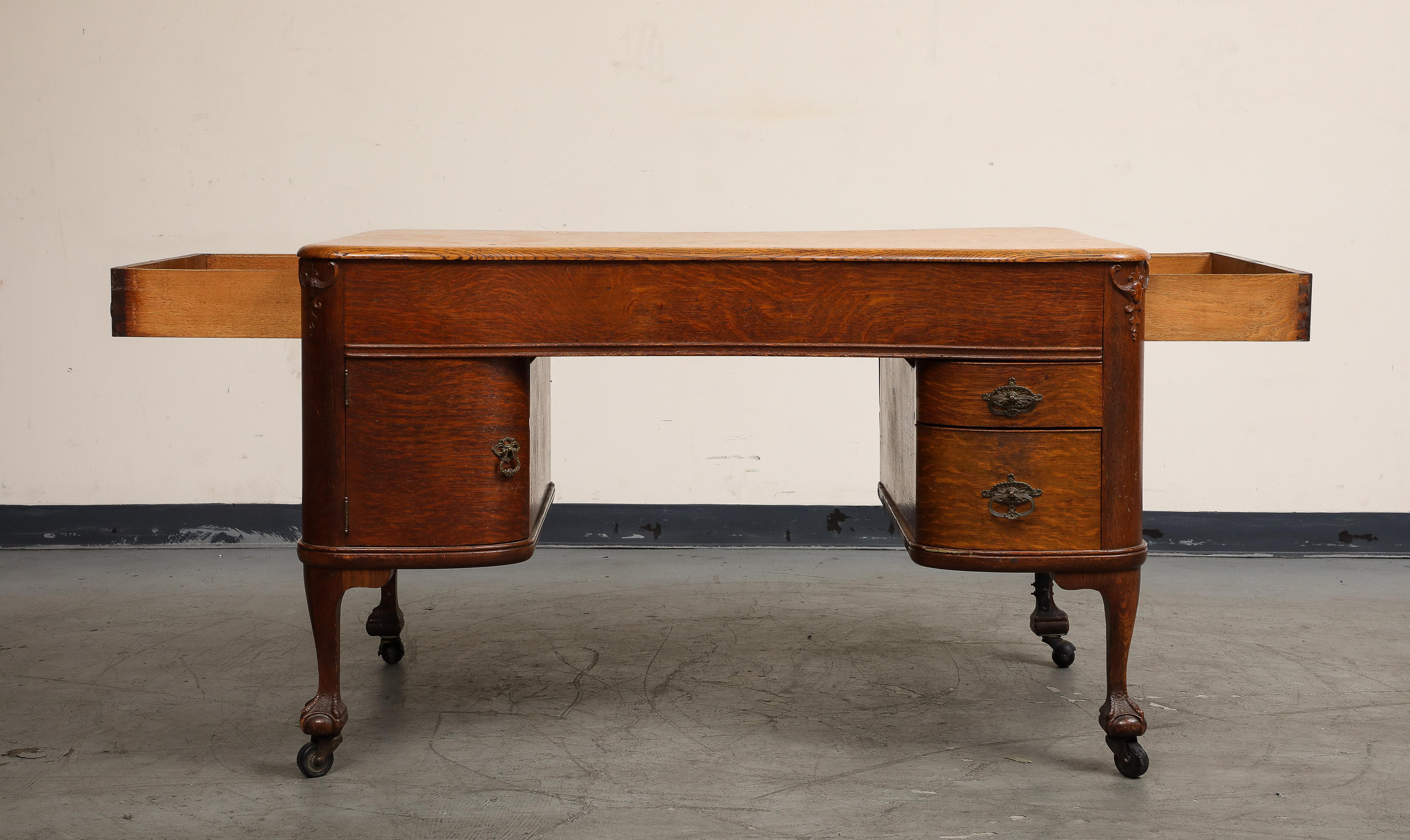English Regency style mahogany partners desk, circa 1930. The top curves inward on each side for two to comfortably share the top. Each side features two drawers and a cabinet, with additional drawers on either end of the desk, all with original