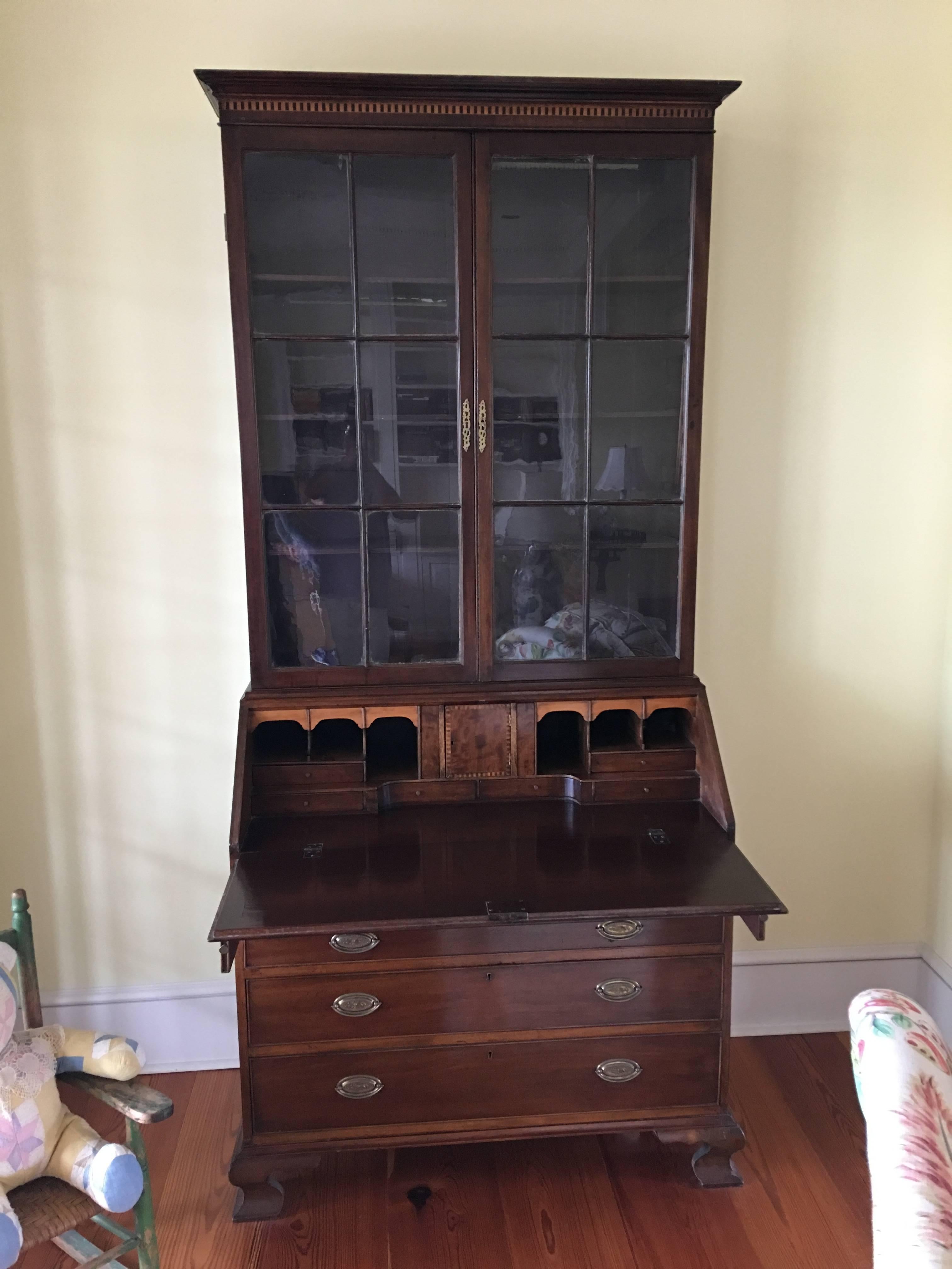 English mahogany secretary bookcase with glass doors over a pull out desk and four drawers, 19th century. It features a molded rectangular cornice surmounting an ebony inlaid plinth, the upper case housing two glazed doors with six panes each, with