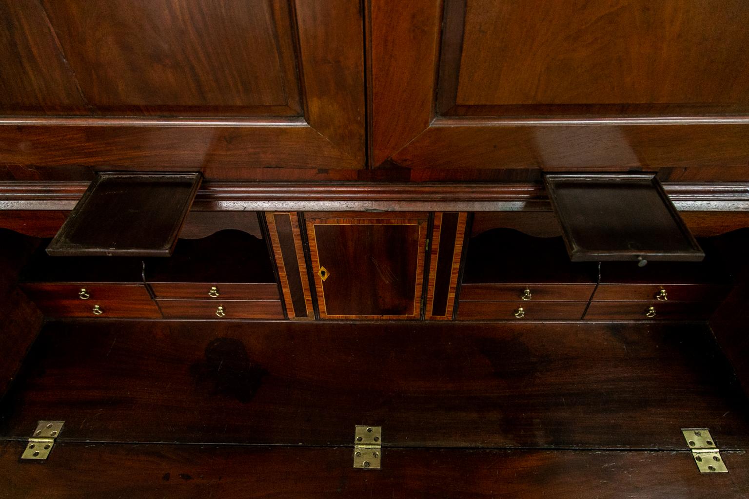 The top of this secretary has shaped raised panels. It has the original four lever lock and key. The top is fully fitted out with drawers and cubby holes. The interior has a central prospect drawer that is crossbanded and inlaid with boxwood. The