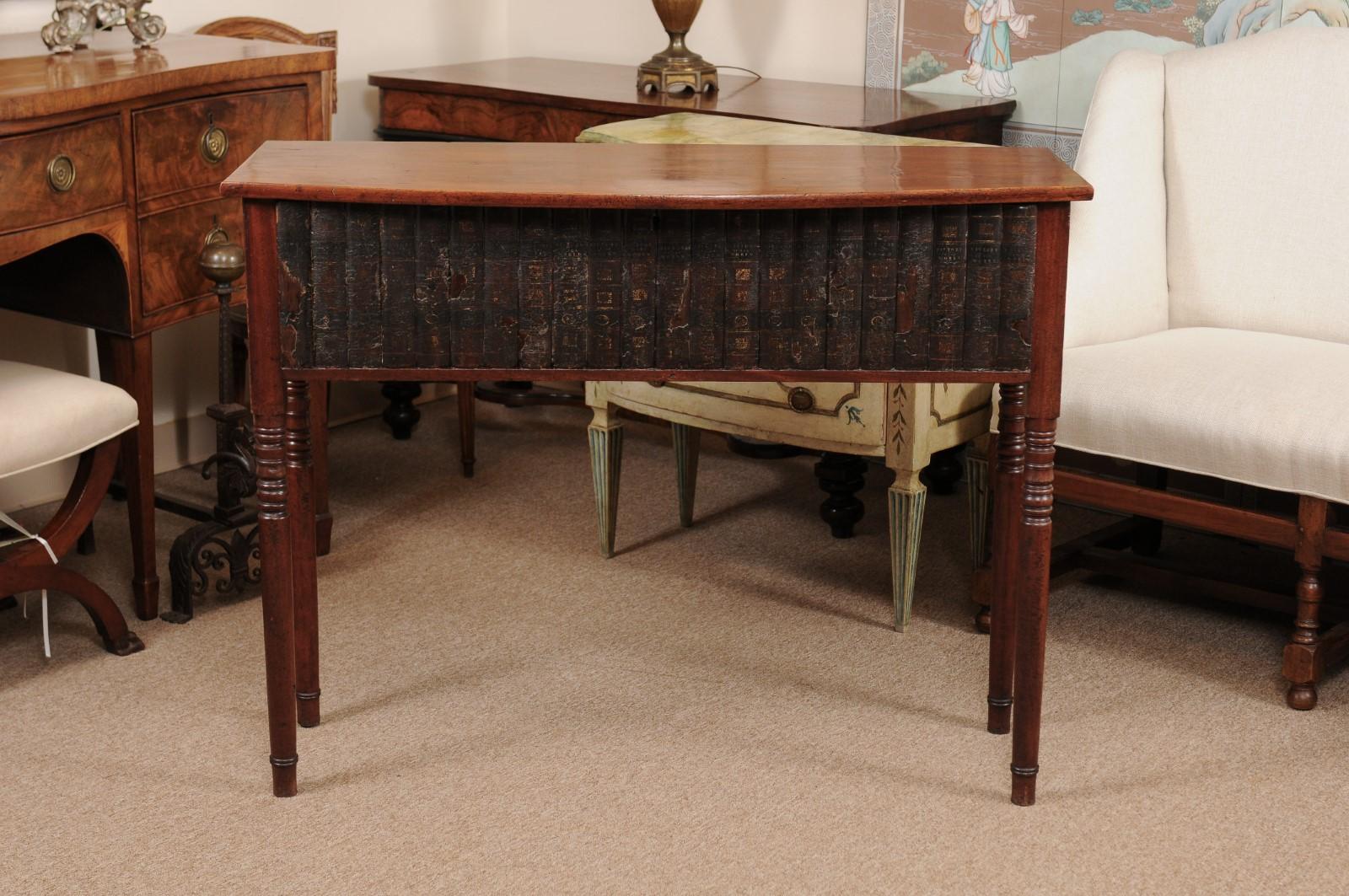 The mid-19th century mahogany server/console table with bow-front top, faux book frieze on drawer below ending in turned legs.
  
  
