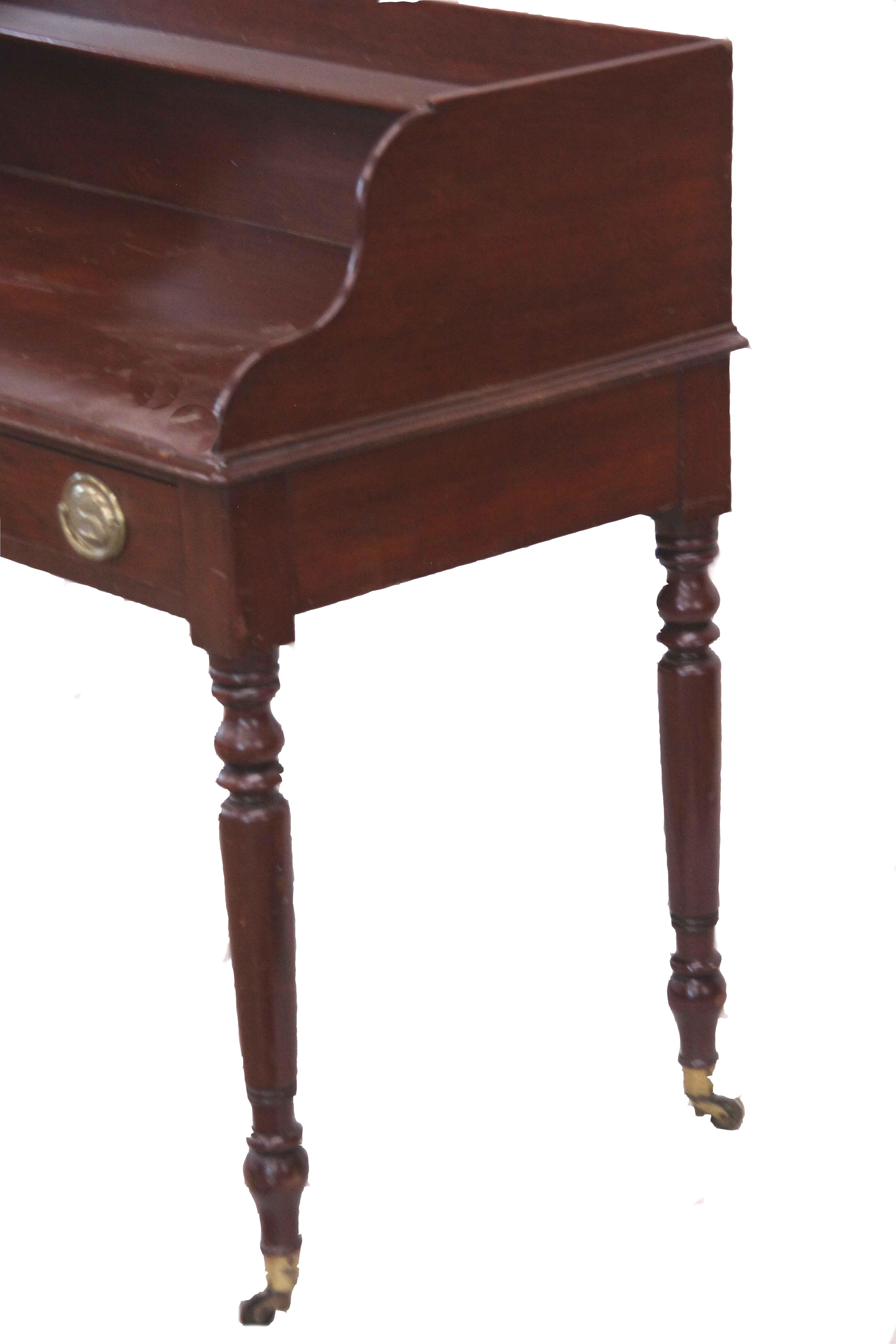 English mahogany two drawer serving table, the top has a gallery surround with a shallow shelf across the back near the crest, two drawers with oval brass pulls, the nicely turned legs with original brass cup castors.  Original finish and patina.