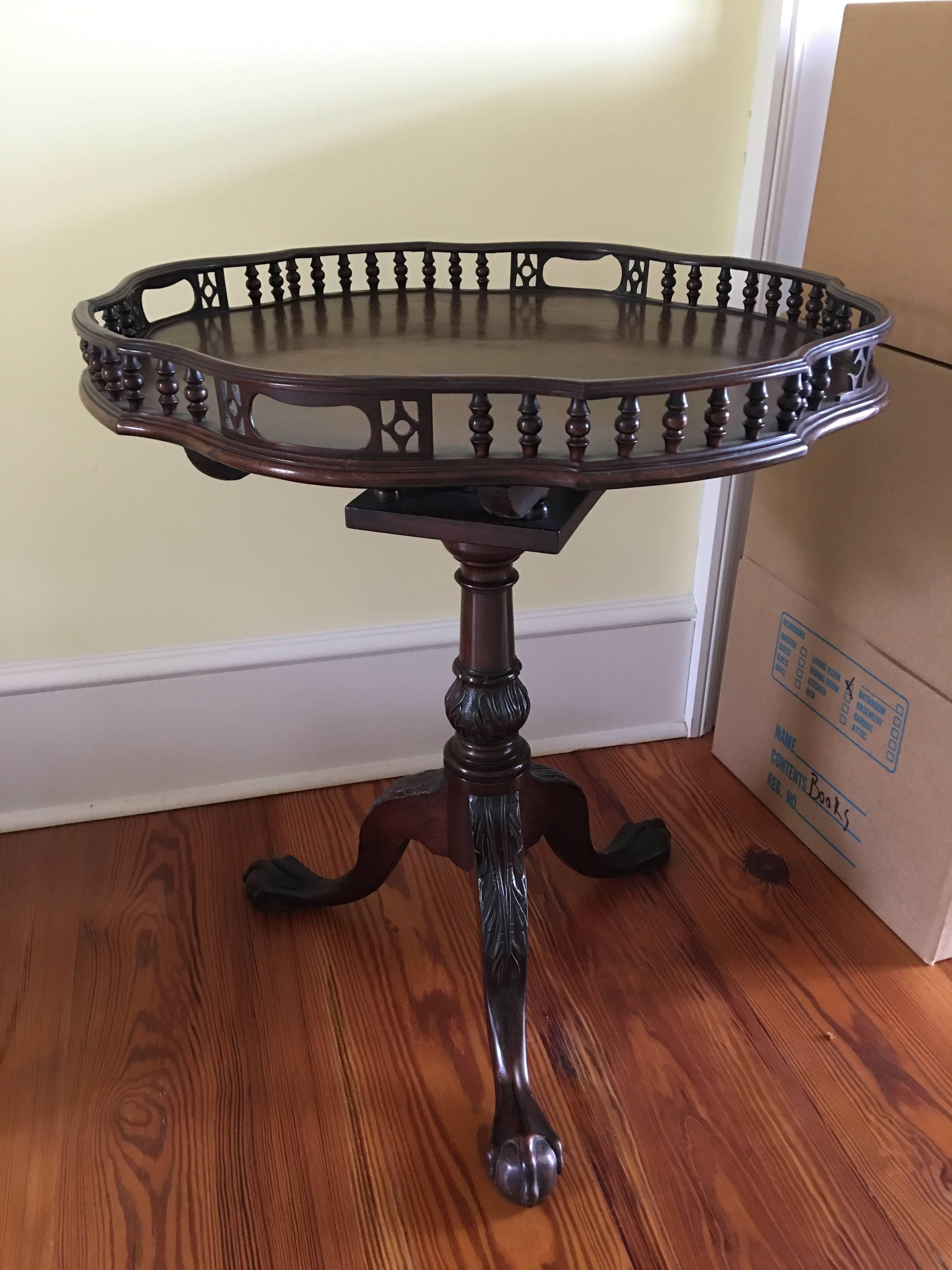 English mahogany shaped and gallery tilt-top table with birdcage, 19th century. It features a shaped and scalloped spindled gallery framing a conforming top, surmounting a birdcage housing a flip-top mechanism, riding above a relief-carved tapering