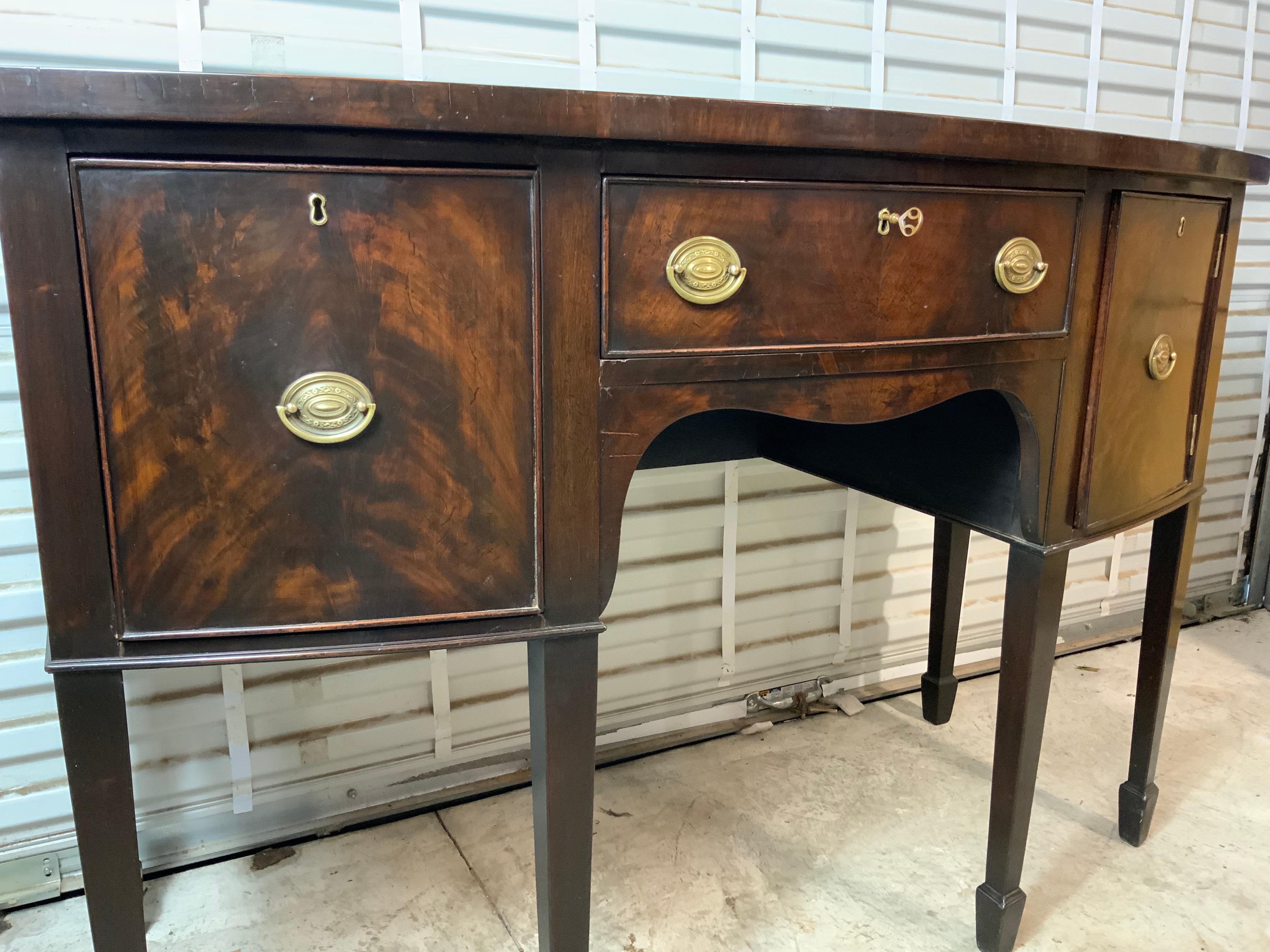 A very nice Georgian Mahogany sideboard early 1900’s on spade feet with two drawers and a door with deep storage compartments.  Old original surface has been lightly cleaned and wax polished and has a great color and patina.  All locks are working