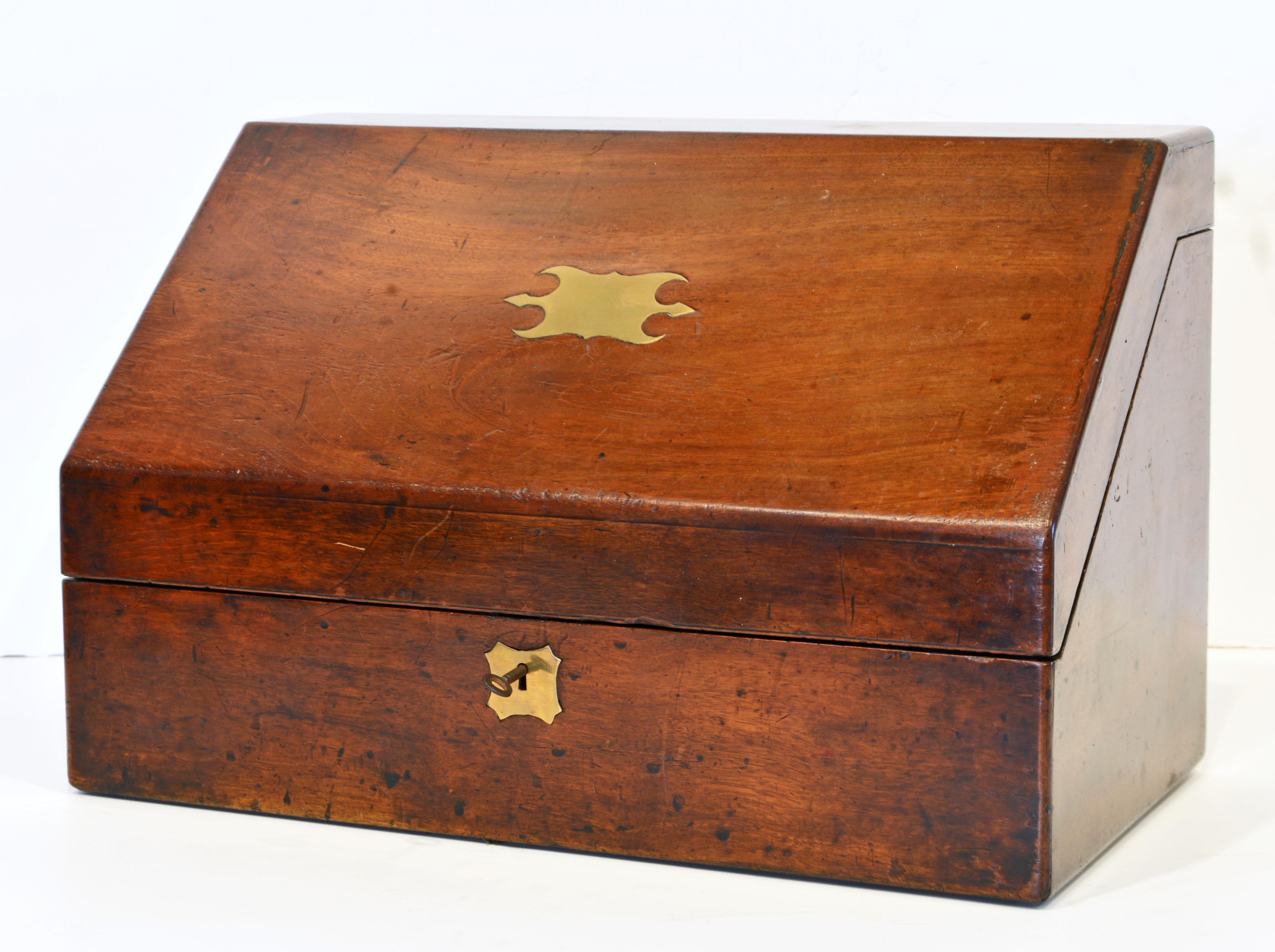 This fine campaign letter box dating to around 1860 features a brass inlaid slant top opening up to an interior fitted with compartments for various paper sizes, a compartment for the original inkwell and one for writing accessories. To the bottom