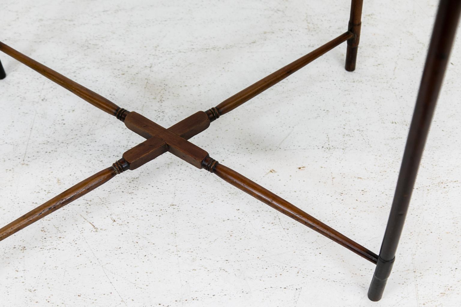 English mahogany spider leg table, has delicate turned legs that end at the top in lambs tongues. The base has a turned cross stretcher that braces the four legs.