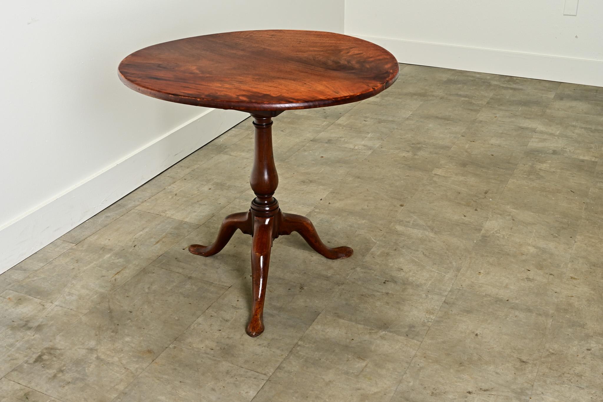 An English round tilt top table with a rare spinning top. The top is made from a single board of solid mahogany which has warped slightly over time. Below the table top you’ll find a metal catch and hinges used for latching and tilting the top, and