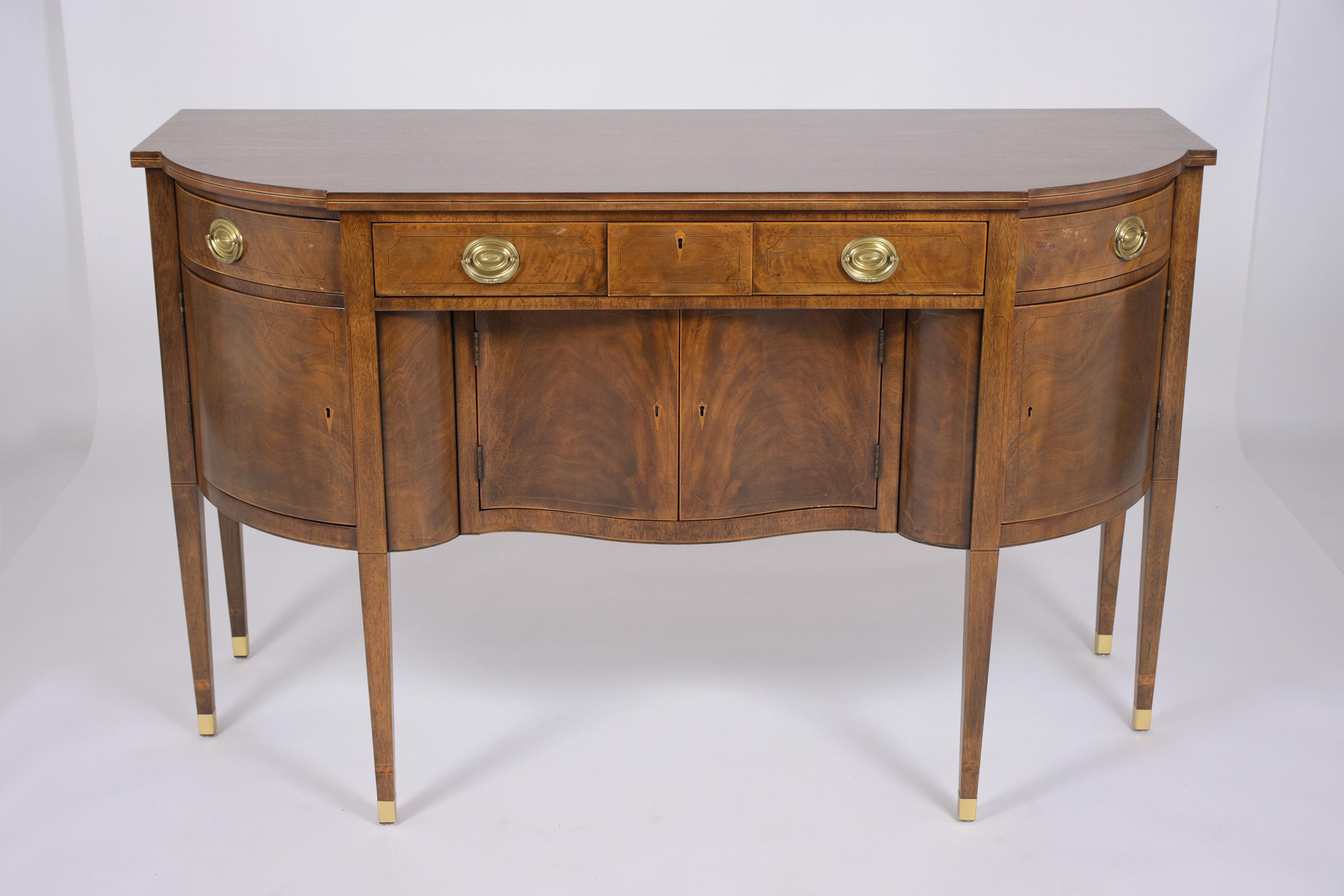 An extraordinary English George III buffet is beautifully crafted out of walnut wood and has been professionally restored by our team of expert craftsmen. This vintage sideboard comes with inlaid marquetry throughout, three drawers with brass pulls,