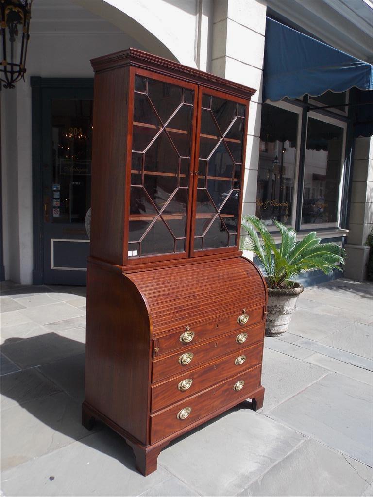 English mahogany secretary with a carved molded dental cornice, two hinged upper case doors revealing three adjustable interior shelves, tambour desk fitted with interior leather tooled writing surface, four lower case graduated drawers with the