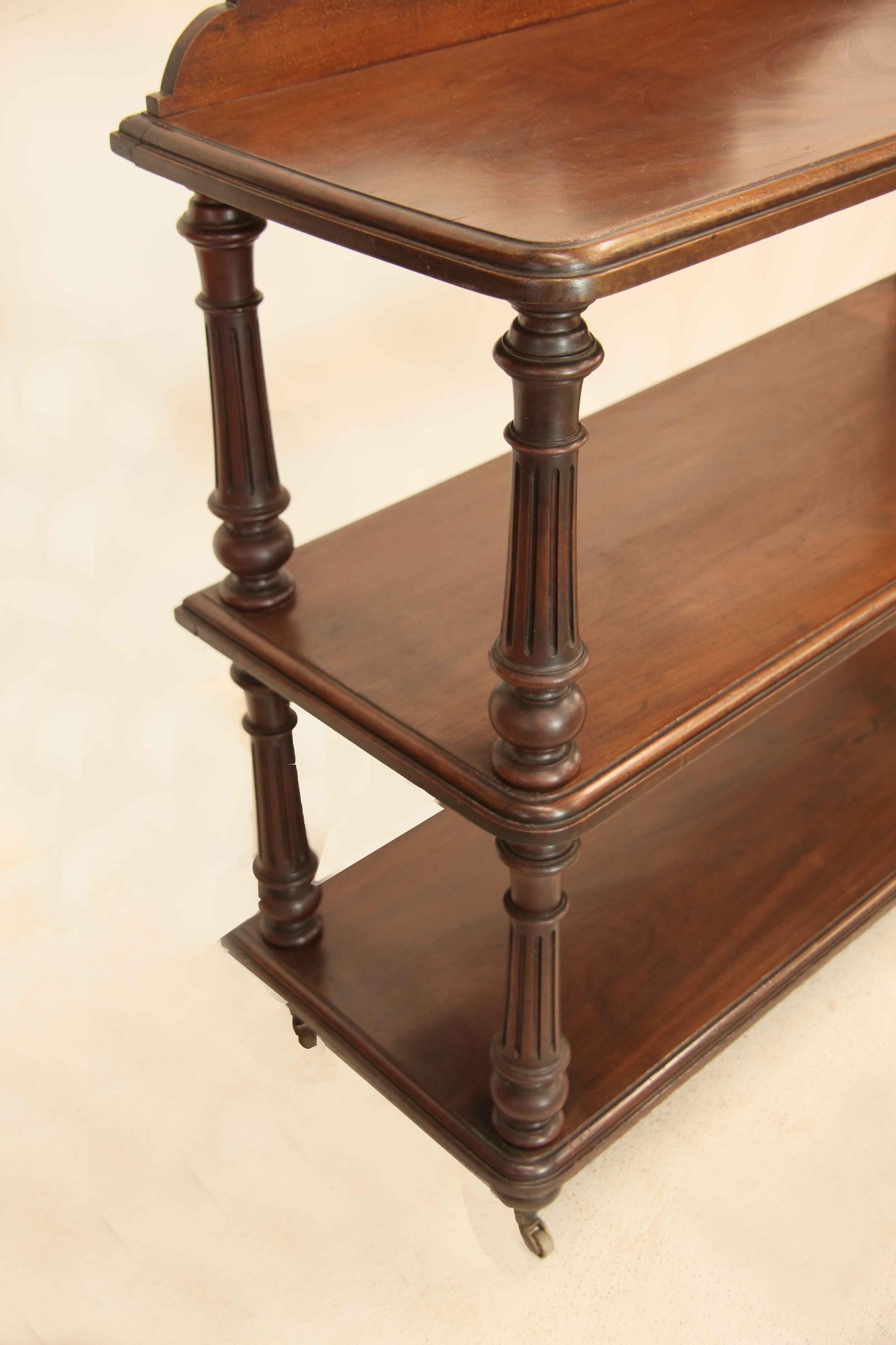 English mahogany three tier buffet, with shapely gallery back, the three surfaces with beautiful color and patina( top surface with minor indentions, see photo), surface edges with cove molding; columns with bold turnings and reeding, resting on
