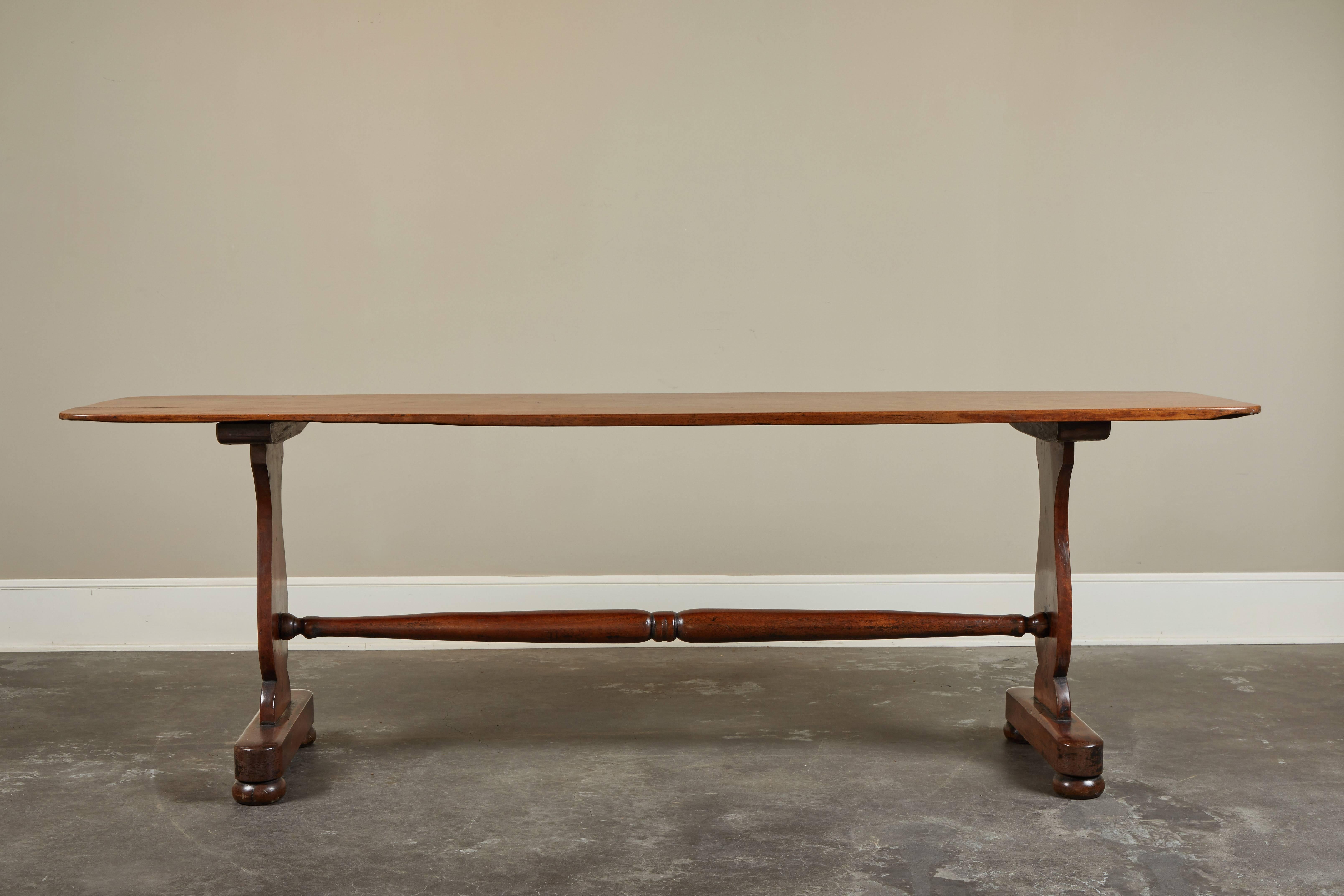 An early 20th century English mahogany trestle table, narrow enough for a sofa back, hall entry or dining room buffet. Clean, trestle legs and single stretcher. Top is a single plank of mahogany.