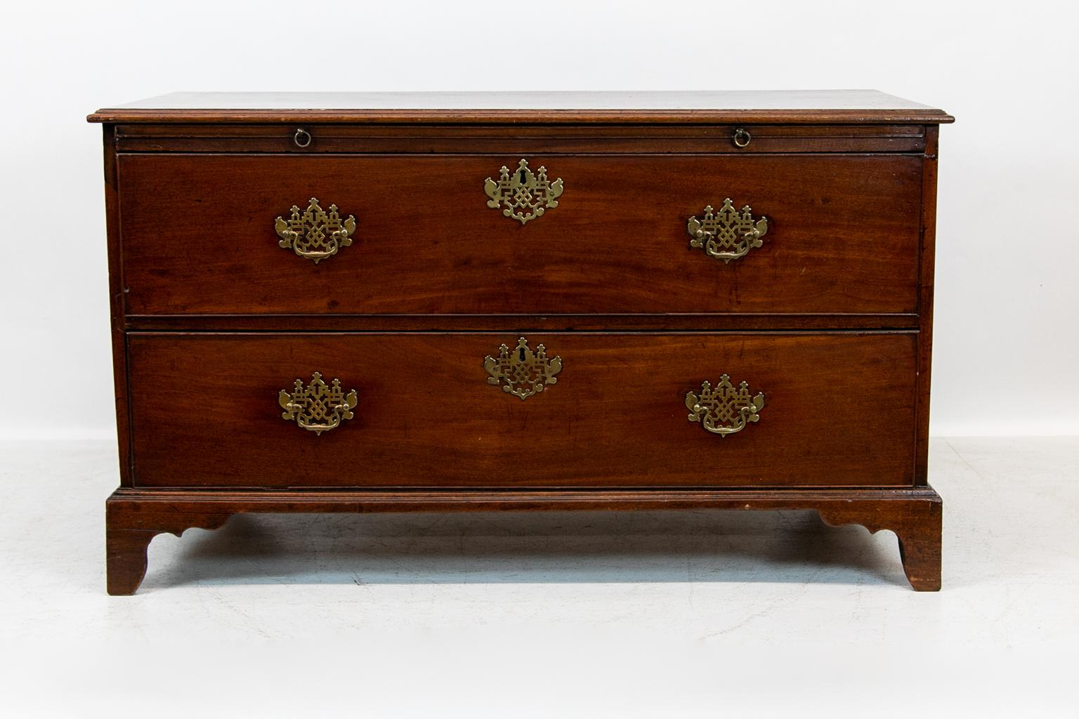 English mahogany two-drawer chest, has a brushing slide, open fretwork brass pulls and escutcheons. There are a significant number of dark stain marks on the top patina.
  