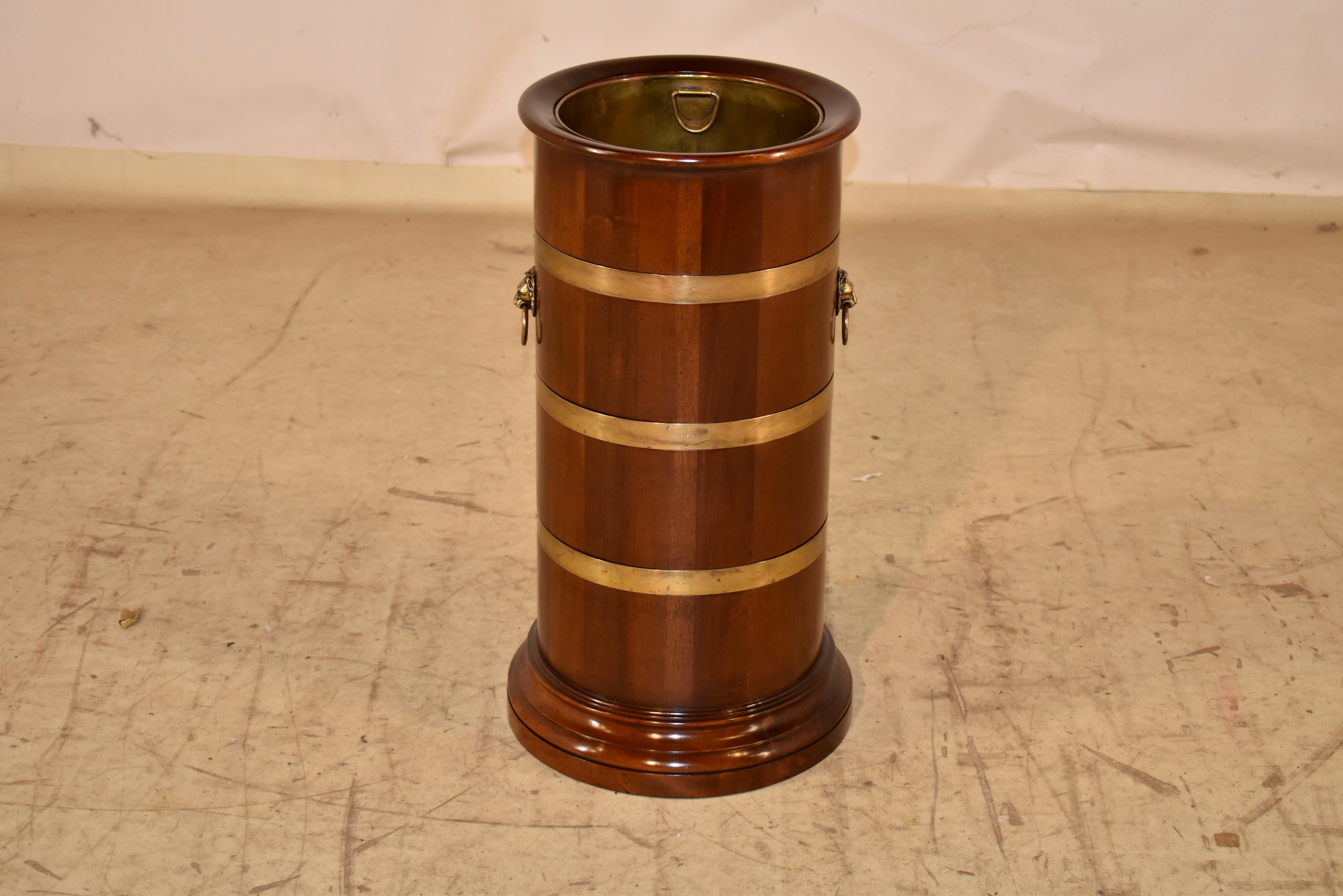Portaombrelli o bastone in mogano proveniente dall'Inghilterra, circa anni '60.  

Il bordo e la base sono torniti e il supporto è composto da doghe di mogano, unite da cinghie di ottone.  I lati sono decorati con maniglie a testa di leone.  Il