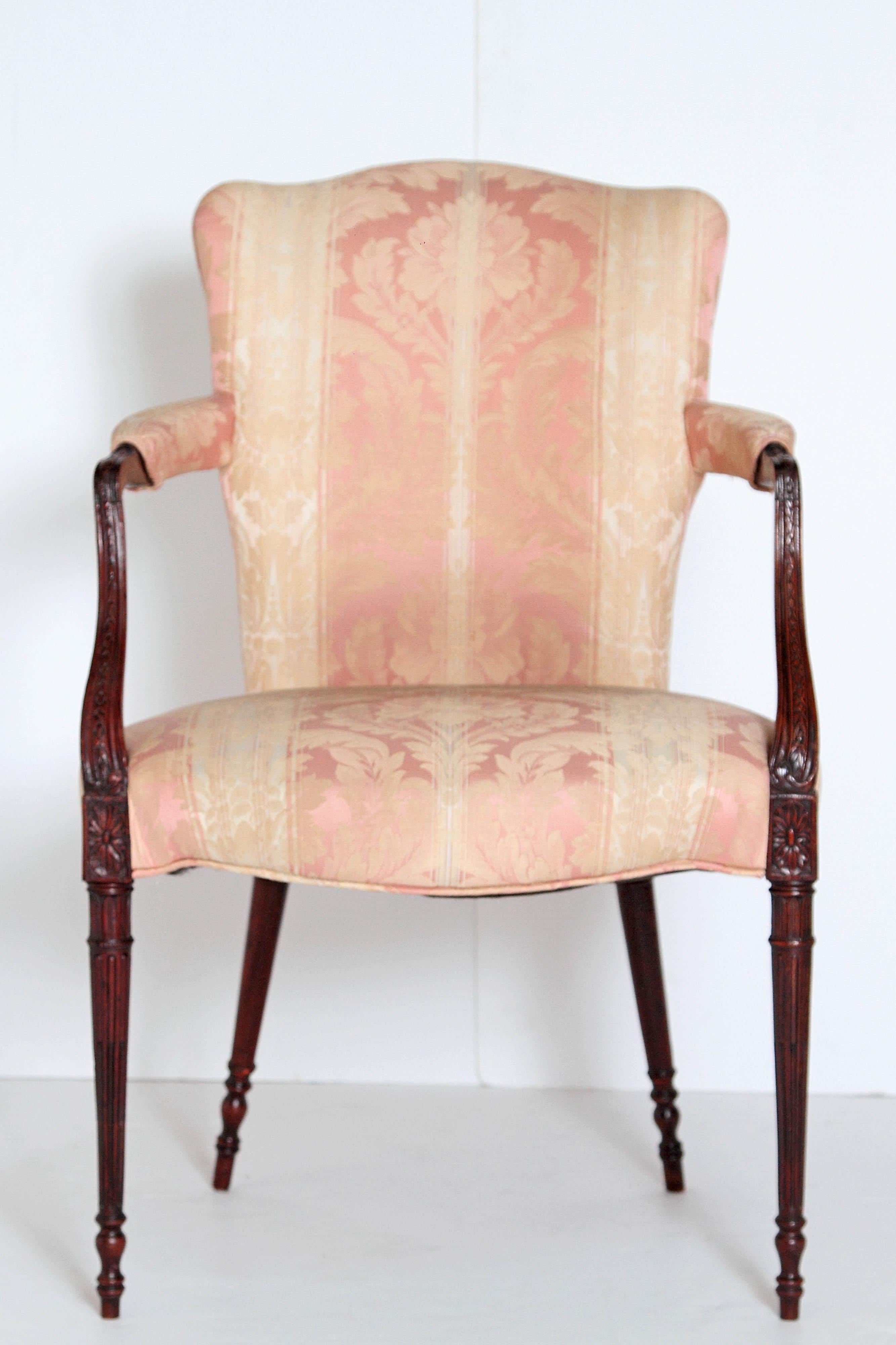 A late 19th century English mahogany open arm chair. Upholstered seat, back and arm rests in cream and pink fabric. Nicely carved arms meet at a rosette block and the reeded tapered legs rest on a cylindrical foot. Late 19th century England.