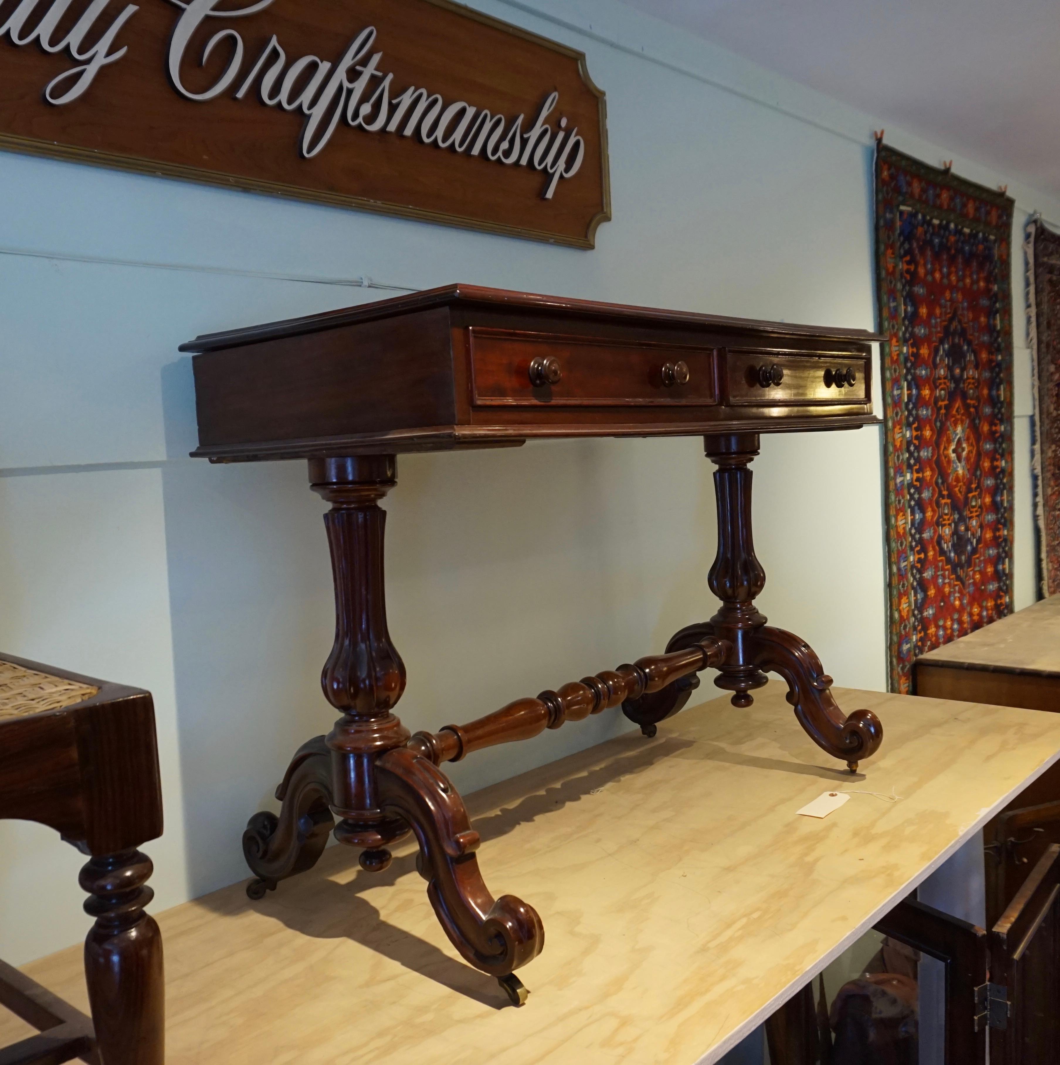Handsome hand carved Mahogany library table on casters, ,1830-1840. Fine detail carving with sturdy scrolling legs united by stretcher. Dovetailed drawers. Recently French polished. Exudes bygone finesse. Easily incorporated in the foyer, study, or