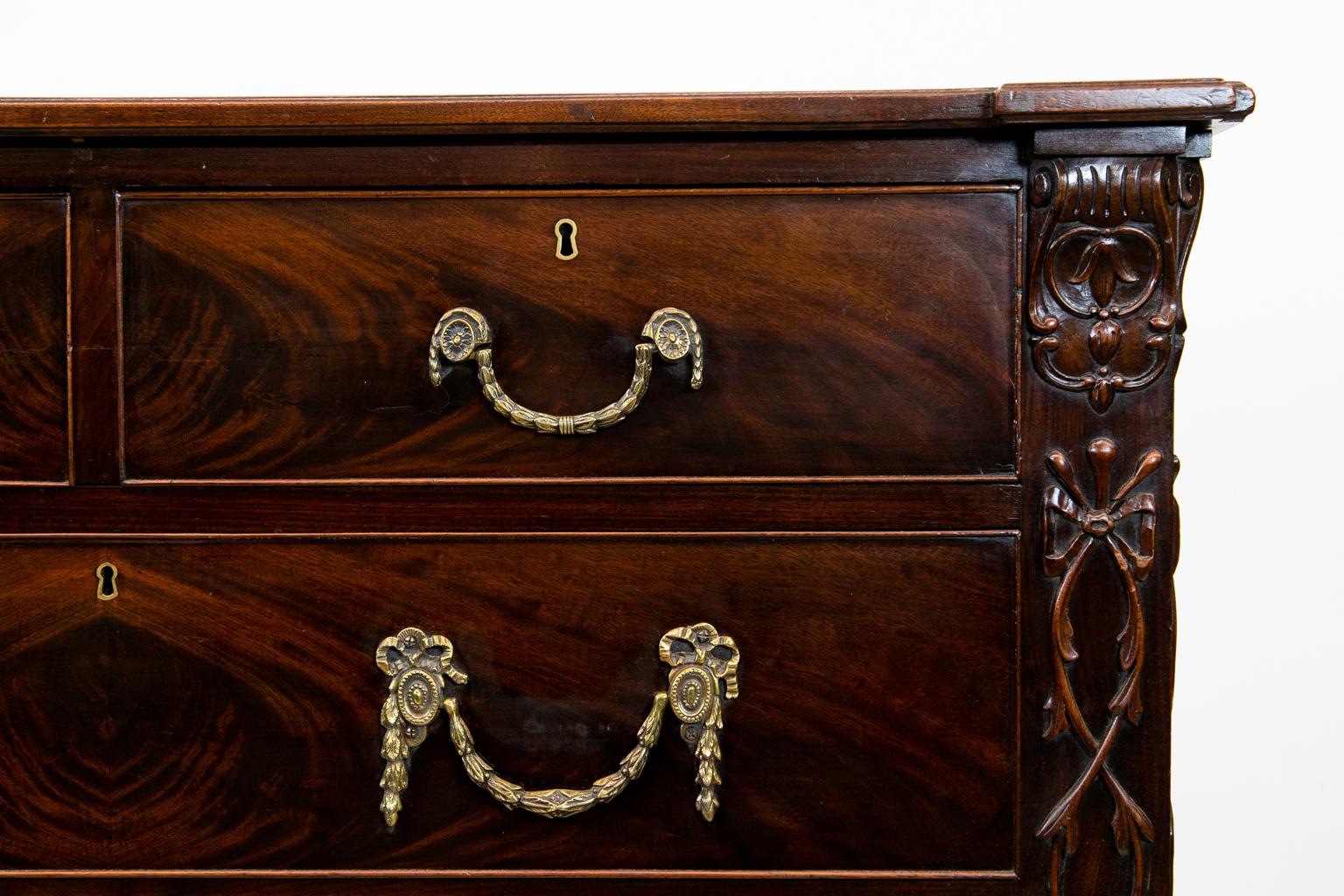 English mahogany William IV chest, with the front and stiles carved with ribbon and floral interfacing designs terminating in feet which are fluted and have a carved rosette, sides with inset panels. The handles are heavy cast brass with acanthus