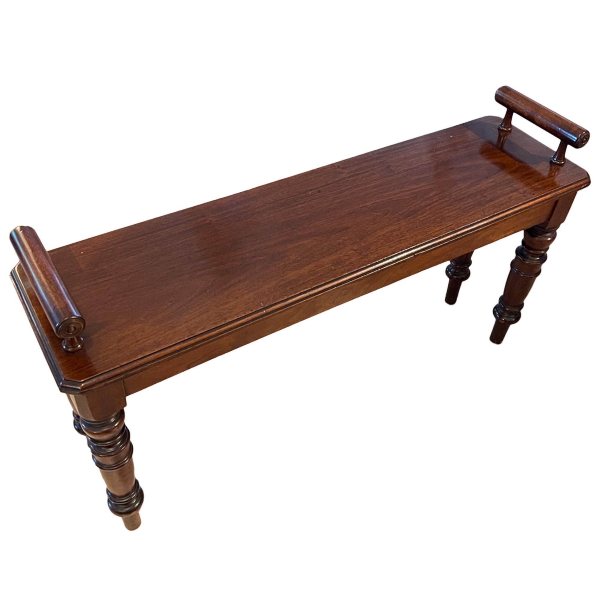 A simple, but elegant mahogany windowseat or bench with a rectangular top, raised bolster ends and turned tapering legs.

A lovely piece of traditional English furniture for a window, end of bed, or hallway. 

Made in England in the 1950s.

Full