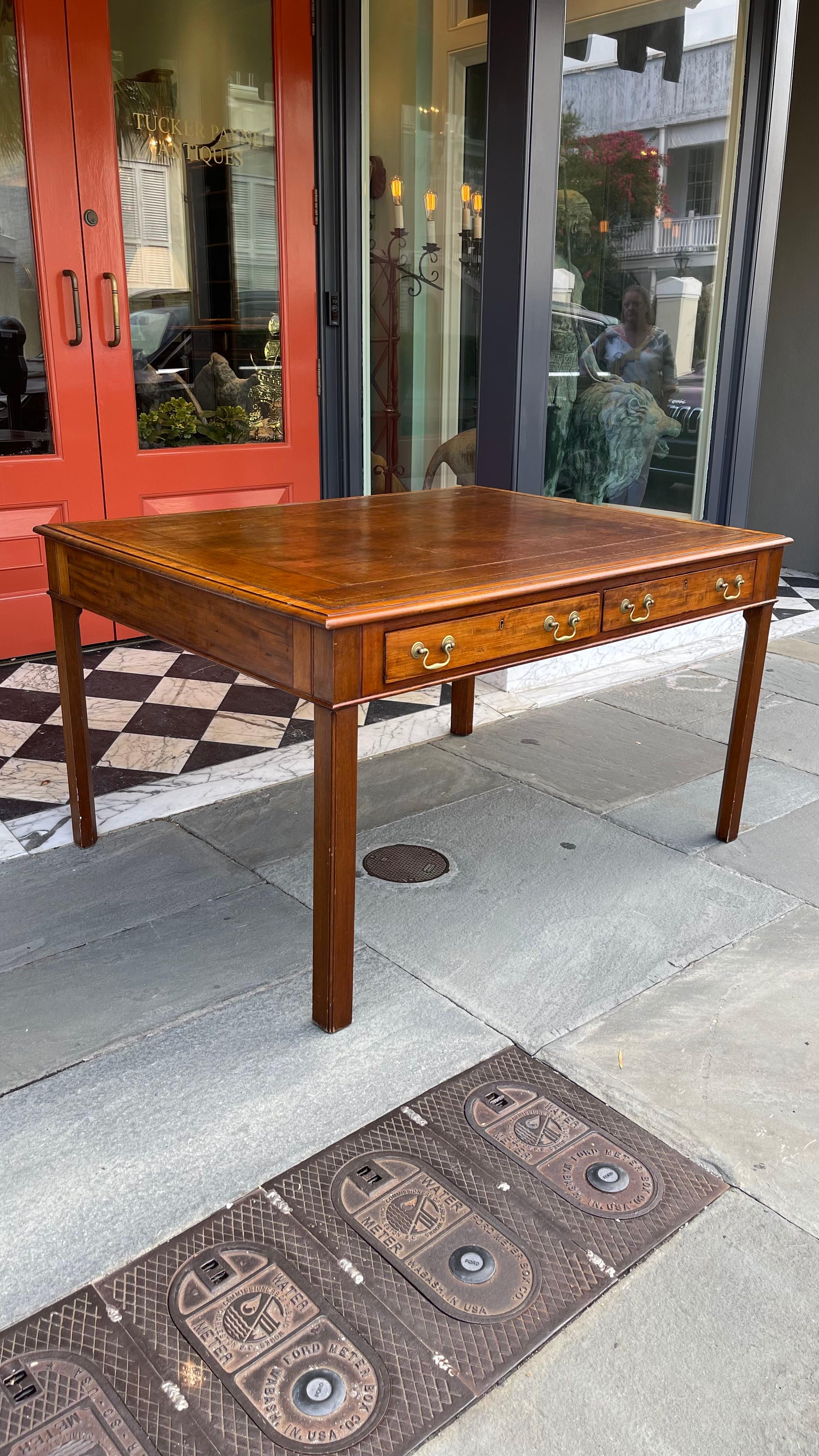 English mahogany writing desk with four drawers. Finished on all four sides so can be used as partners desk or floating in room. Leather surface has lovely patina with leather tooling and gold gilt accents.