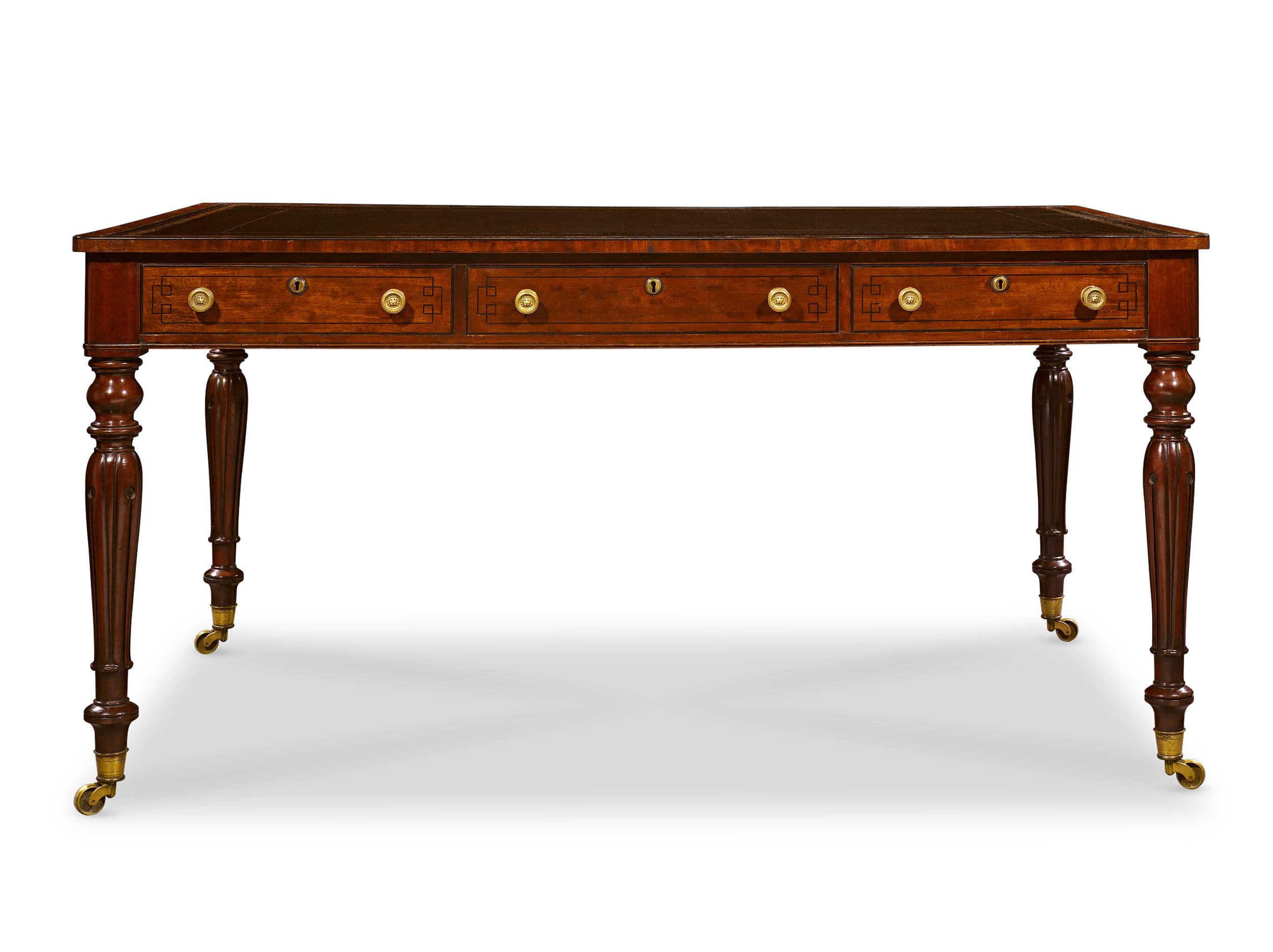 This exquisite writing desk is crafted of rich mahogany and features the straightforward design prevalent in England during the early 19th century. A luxurious leather-covered top presents an ideal writing surface, and three lockable drawers, each