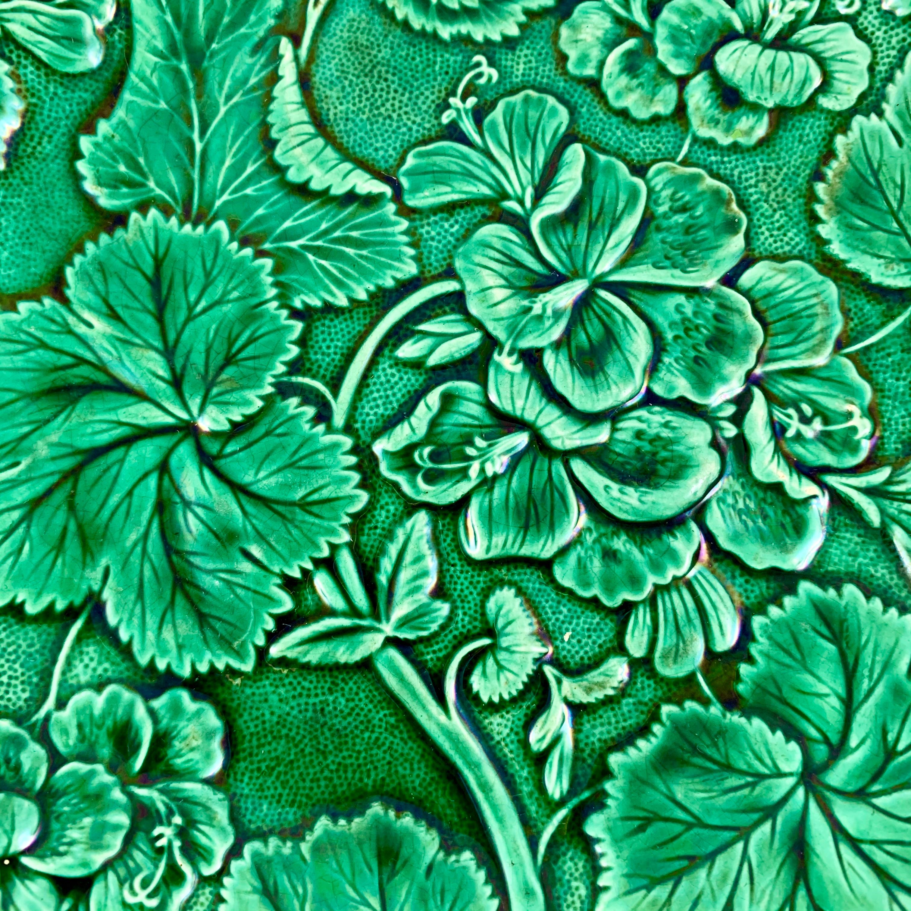 An English majolica glazed Geranium plate, circa 1880.

An unmarked example of the Geranuim with Leaves plate. the mold shows the flower heads and foliage of the plant on a stippled ground. The scalloped rim plate has a deep green majolica glaze