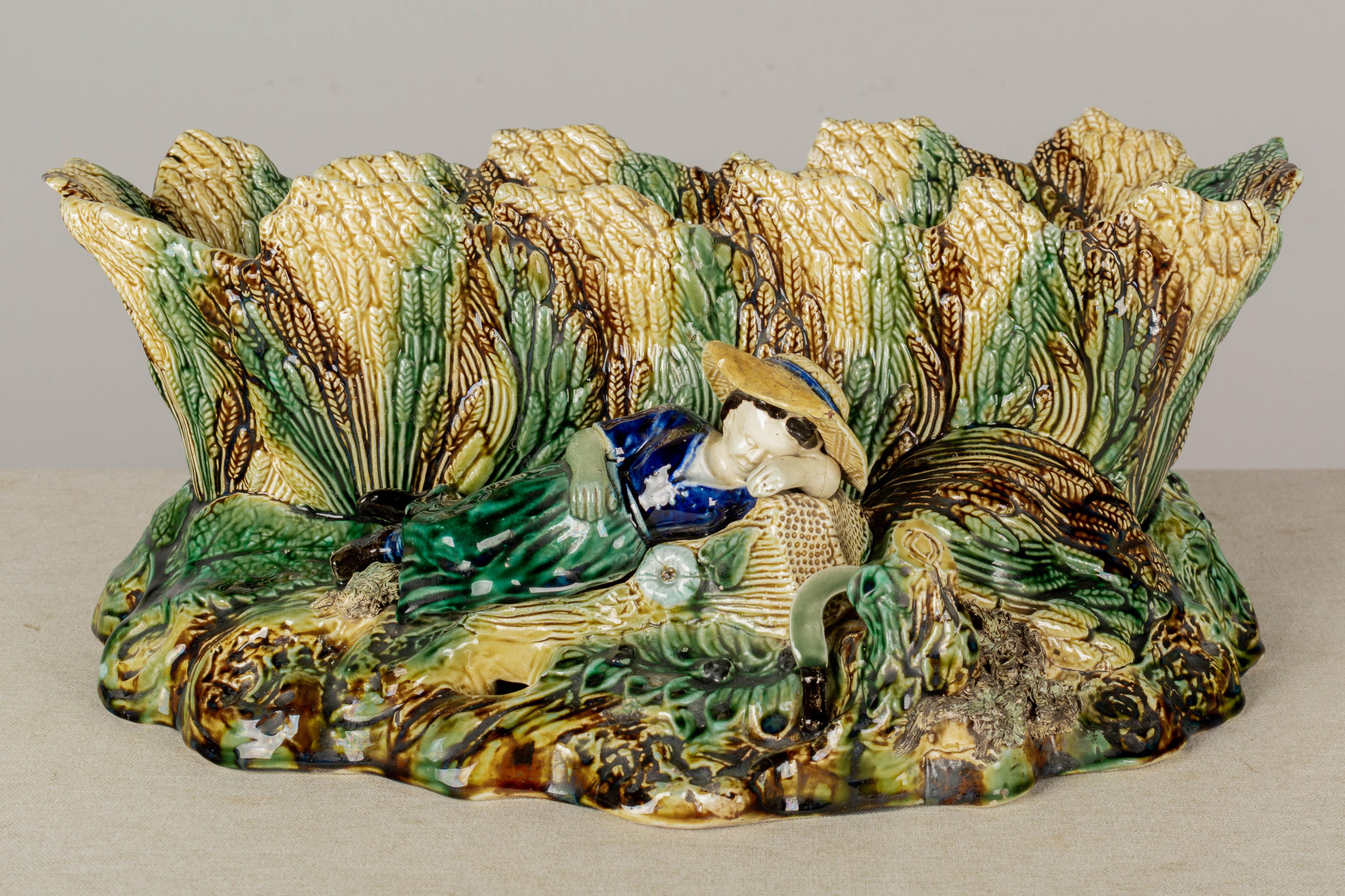 A large English Majolica glazed ceramic jardinière, or planter, oblong shape depicting a sleeping maiden in a field of wheat. Vividly colored glaze in green, brown, yellow ocher, and cobalt with dark brown interior. Perfect for the display of