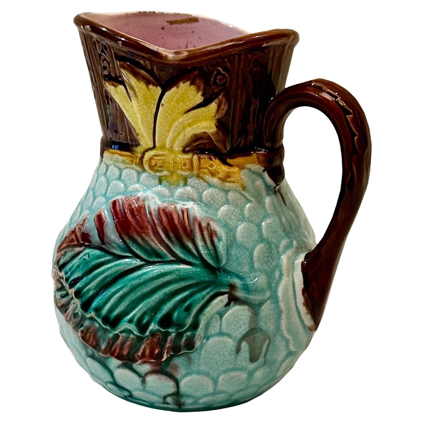 An antique Majolica leaf pitcher in beautiful shades of aqua, yellow, green and brown with a pink interior. England, circa 1890s.