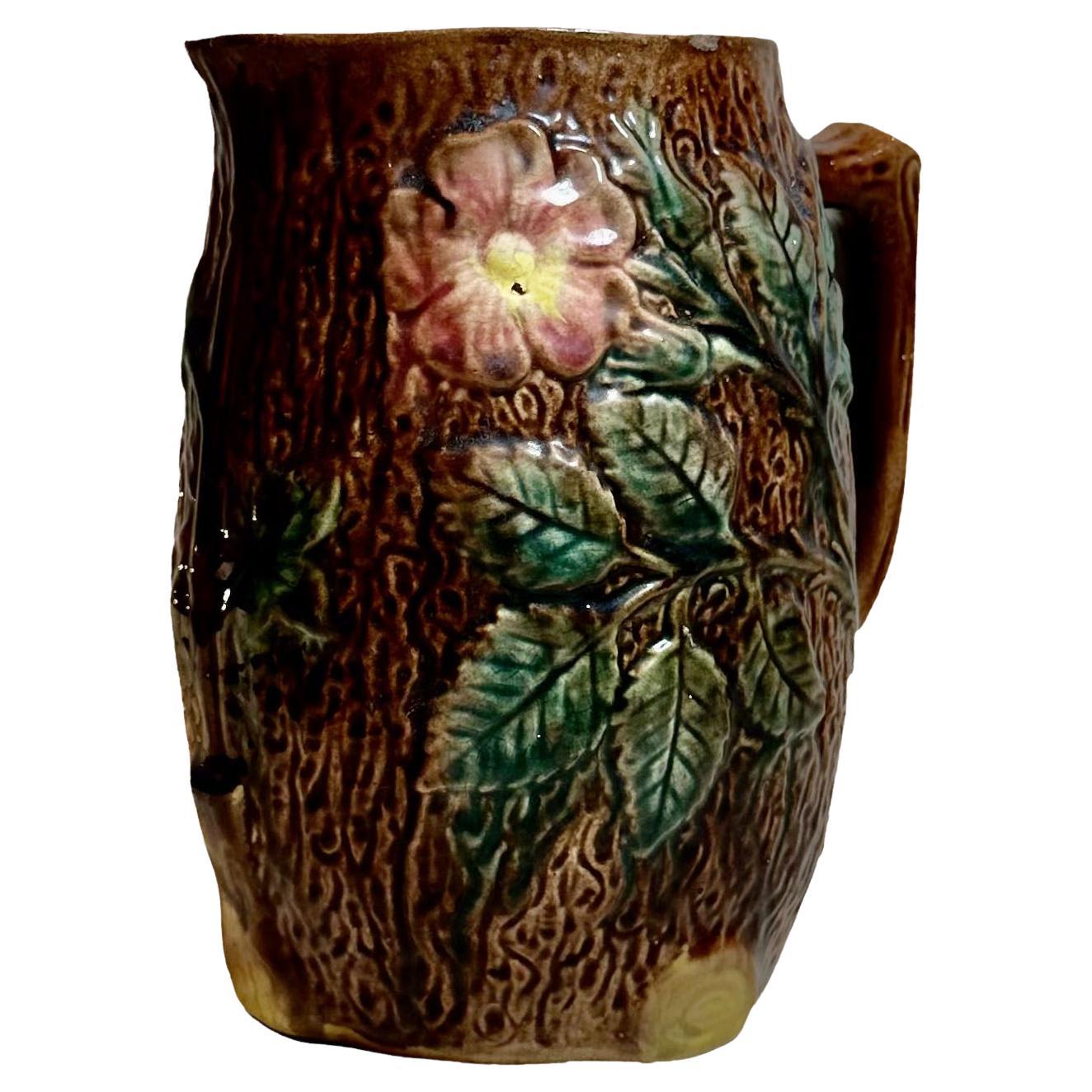 A late 19th century majolica picture featuring pink pansies with lemon centers and green leaves. 