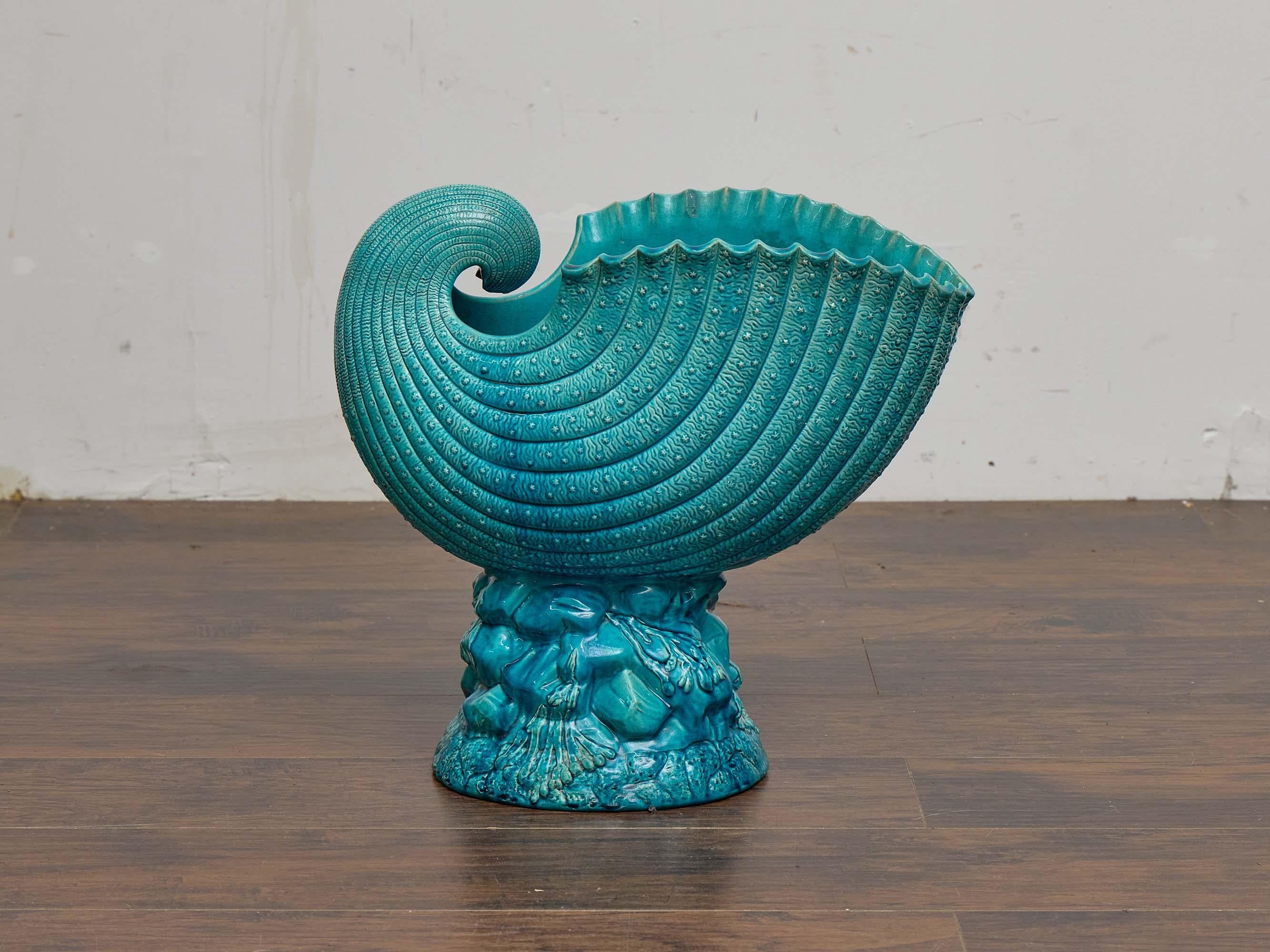 Un sorprendente vaso in maiolica inglese con conchiglia nautilus risalente al 1880 circa, modellato con un vibrante smalto turchese. Il vaso ha la forma di una conchiglia finemente scanalata con una superficie strutturata, le cui curve a spirale si