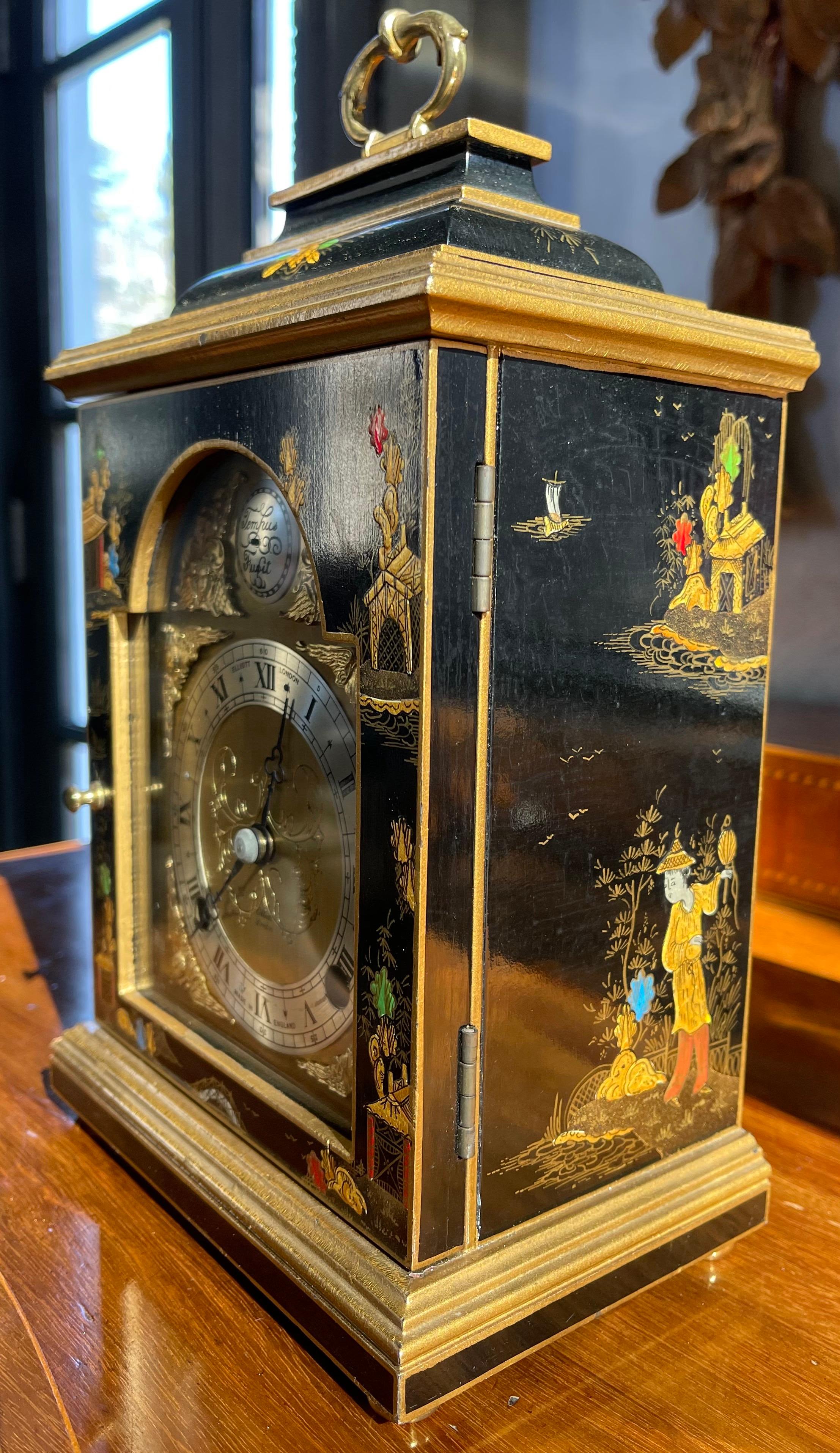 A black lacquered chinoiserie decorated mantel clock by Elliott of London. The case is finely decorated with garden scenes, pagodas and floral motifs. The brass dial with angel spandrels and silvered chapter ring with roman numerals, surmounted by a