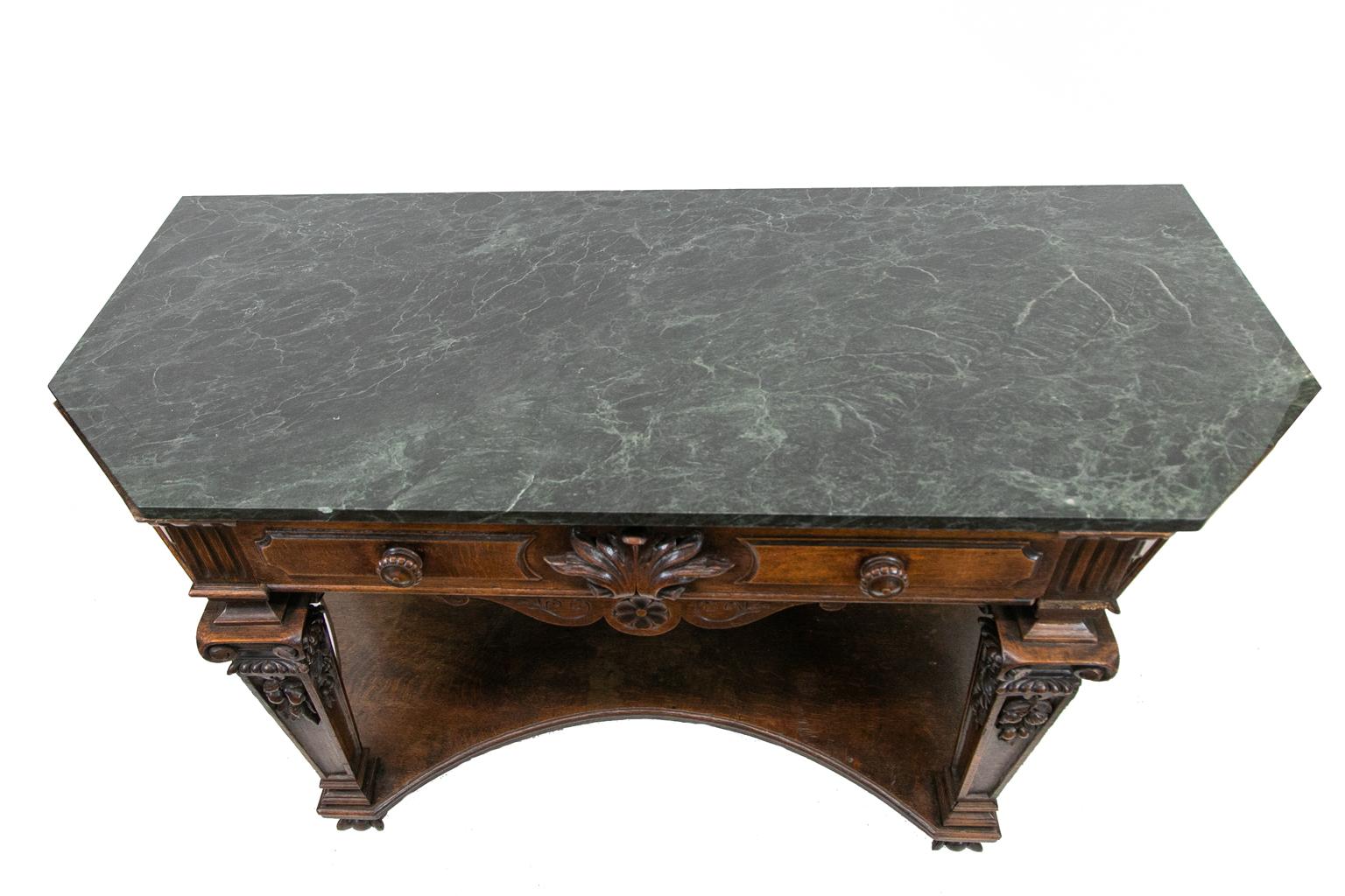 English marble top console table, with the drawer having an acanthus leaf carved in high relief. The chamfered sides and drawers have molded panels. The legs have carved volutes surmounting carved gadrooning which a tops fruit carvings in high