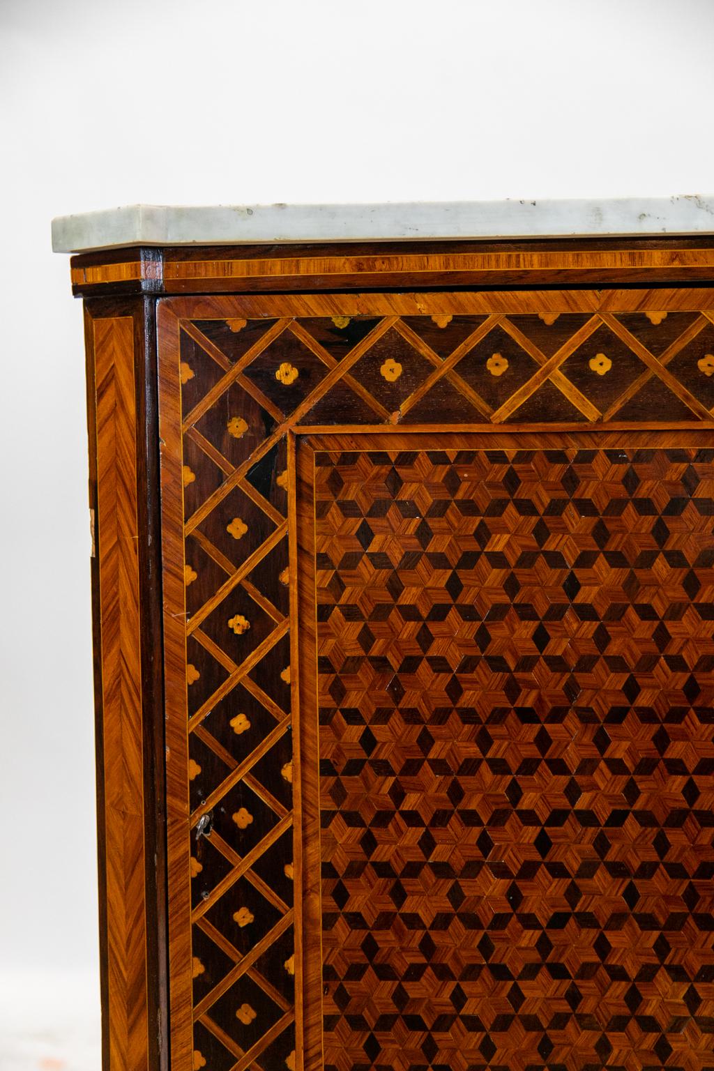 English marble-top inlaid corner cupboard, is inlaid with exotic woods. The door has a recessed panel inlaid in a square illusion pattern framed by rosewood, which is inlaid with stylized flowers and bindings in geometric patterns. The feet