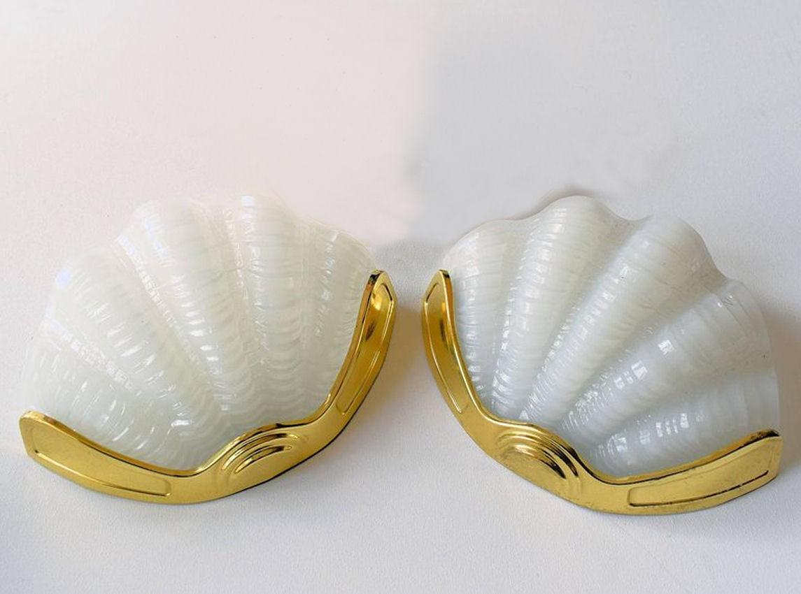 A beautiful matching pair 1930s Art Deco wall lights of shell form. The gilt frames are in very good original condition which when fitted to the wall hold the beautiful soft milk white opaque glass shades firmly in place. Truly beautiful and will