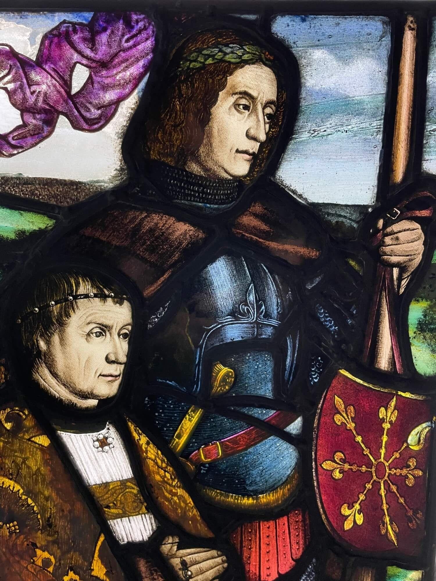An antique English medieval style leaded glass window circa 1850 in Tudor revival style depicting an armoured knight holding a banner beside a priest as if standing at the edge of a great battle. Vibrant colours and sharp details make this stained
