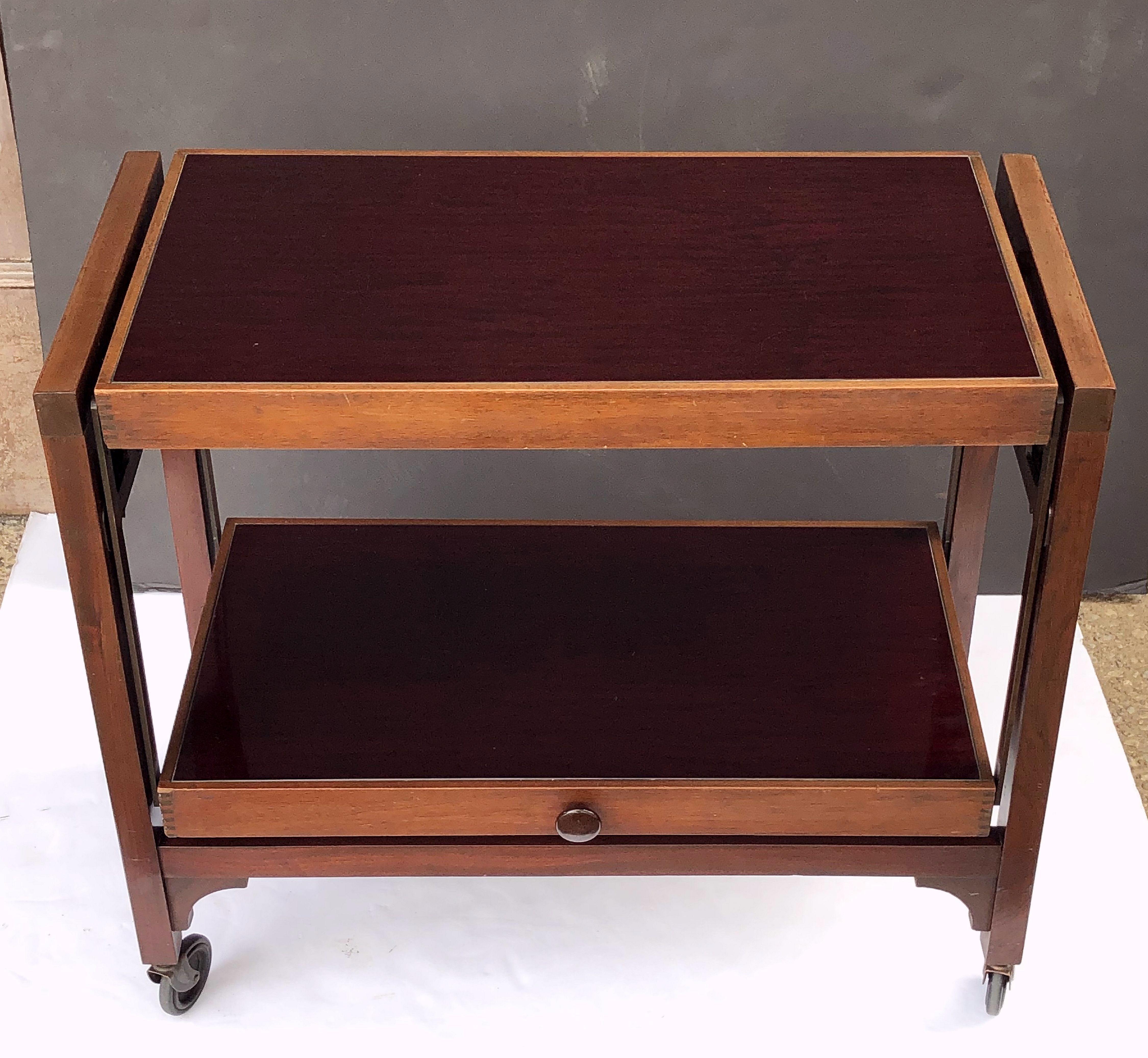 A fine English metamorphic drinks trolley or bar cart (also known as a besway or trimagic table), which converts into a useful occasional table via a mechanism triggered by pulling a knob situated on the middle tier.

This design was patented by