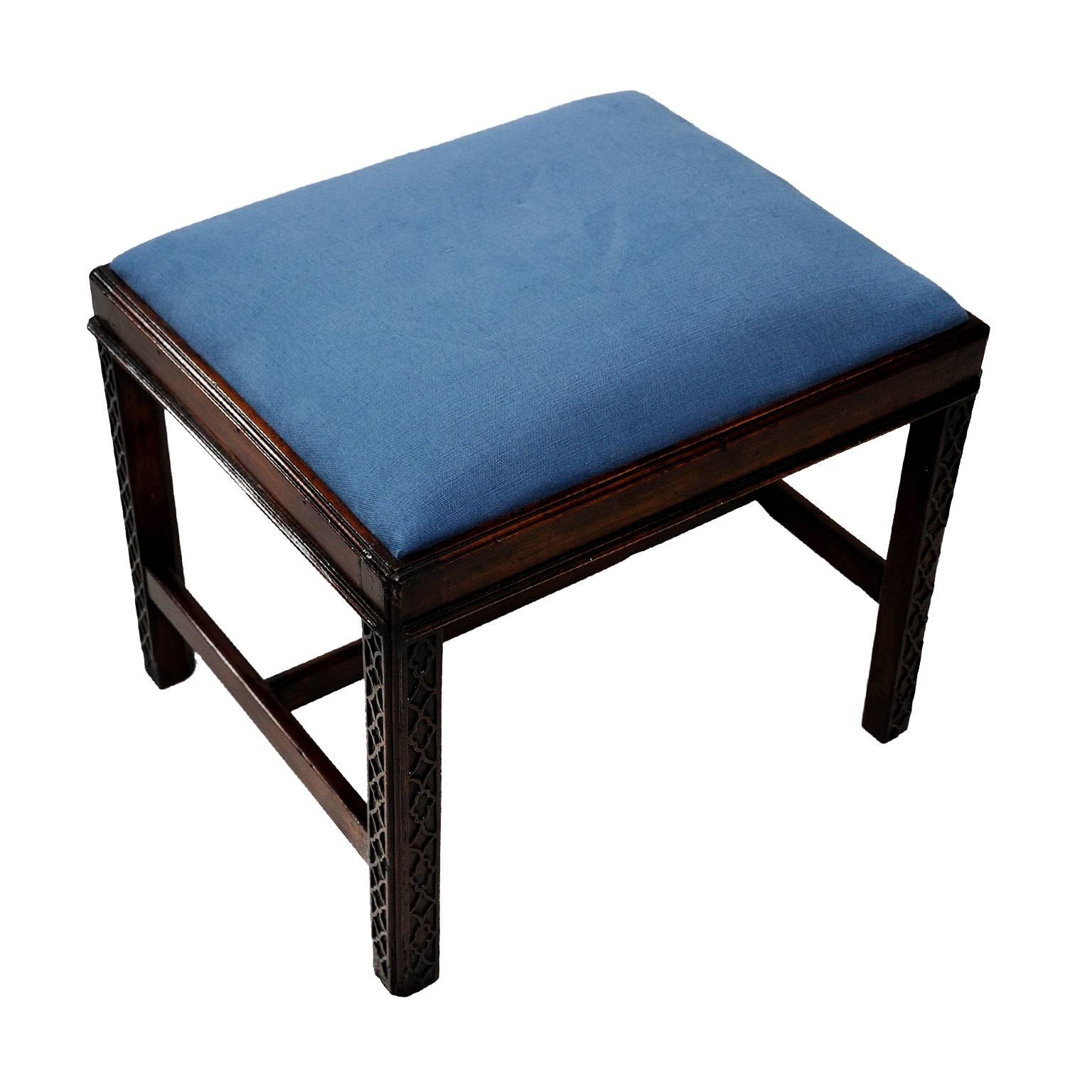 This is a rather lovely English mid-18th century George III mahogany Chippendale style stool, featuring blind fret decoration to the legs and upholstered in beautifully complimentary blue Scottish linen, circa 1760.