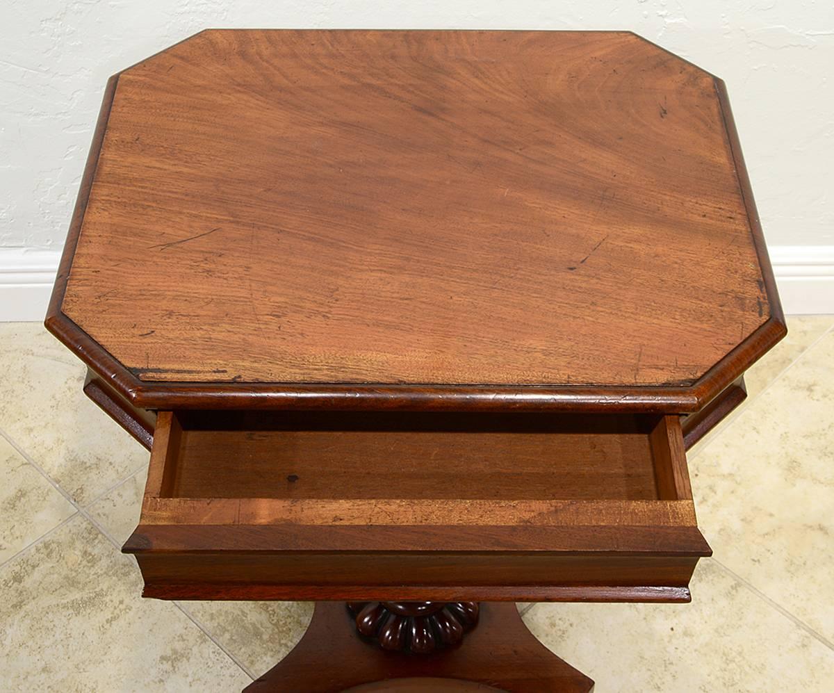 This fine William IV Mahogany occasional table features an octagonal top above a frieze concealing one long drawer supported by a carved center pedestal resting on a shaped base with four carved feet and casters.