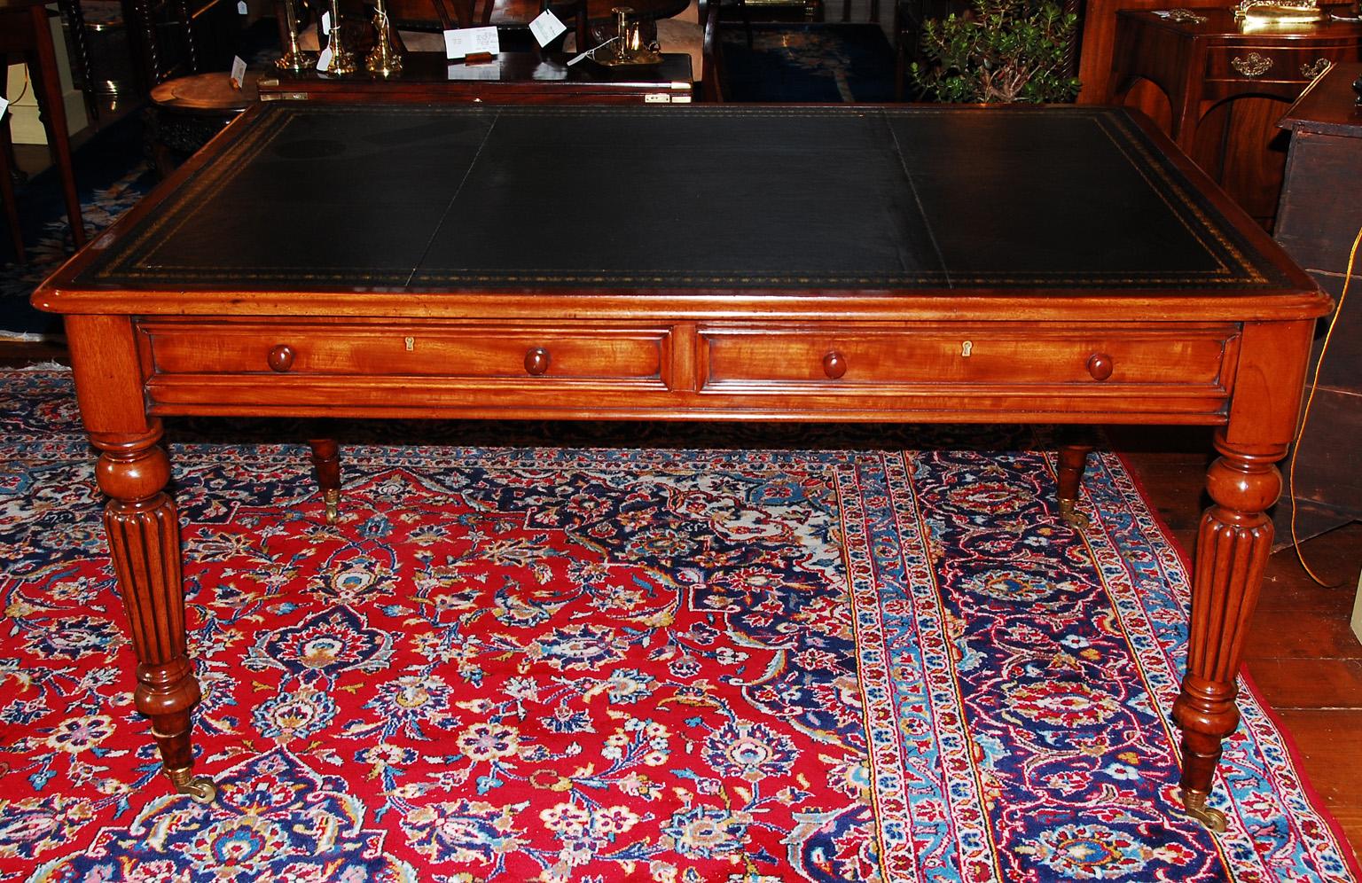 English mid 19th century mahogany executive writing table with reeded, tapered, turned legs, two molded edge drawers and replaced black hand tooled and dyed leather writing surface. This handsome writing table has drawers on one side, the other