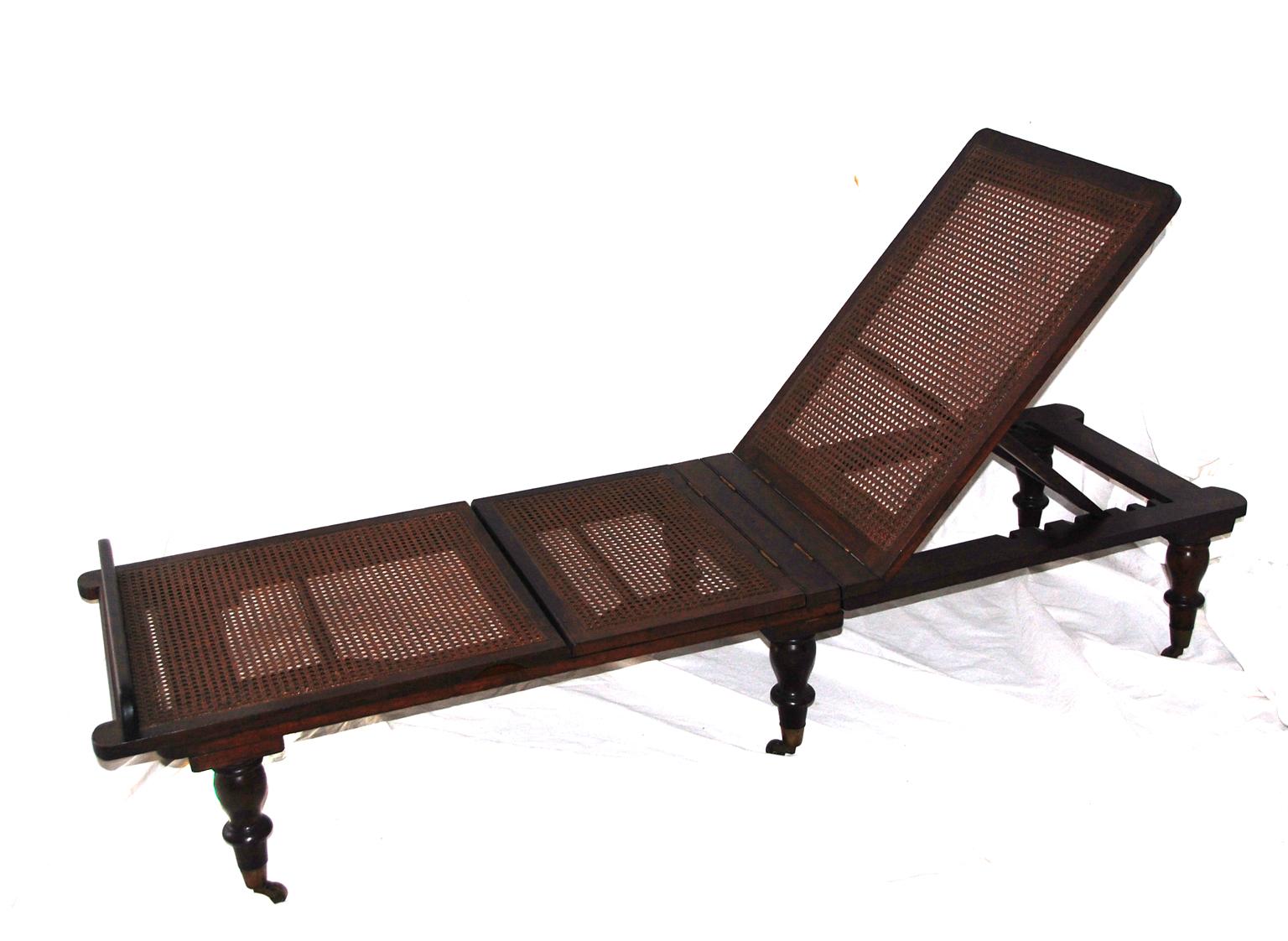 English campaign chaise lounge in mahogany with linen cushions. This folding lounge, made for a military officer is extremely adjustable. It can be used totally flat as a bench or even a coffee table or both the top and two sections of the bottom of