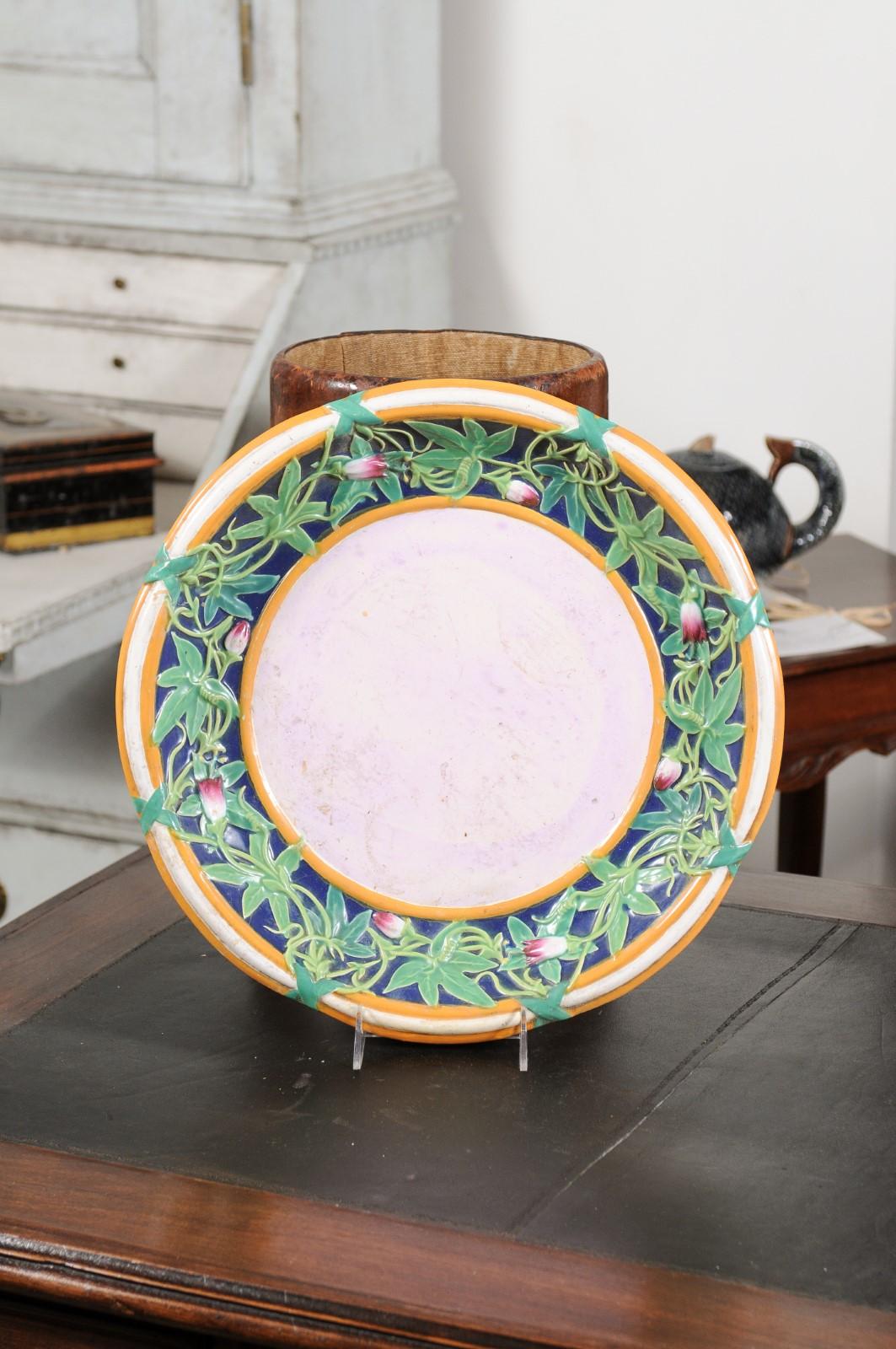An English Minton Majolica platter from the mid 19th century, with floral motifs. Created in England during the 1850s, this Minton Majolica platter charms us with its ingenious design. Scrolling ivy with petite pink flowers adorns the platter border