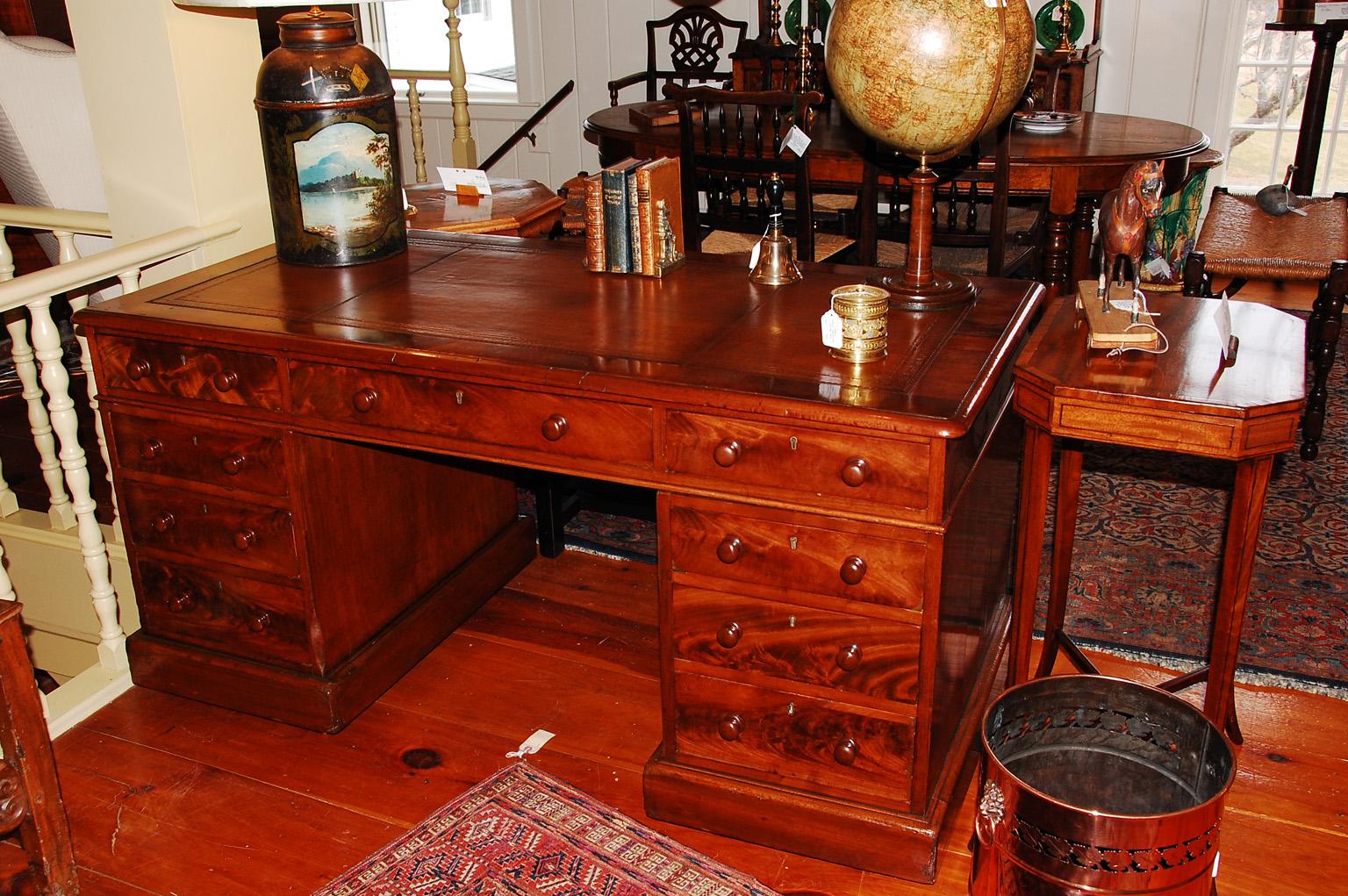 English mid 19th century mahogany and flame grained mahogany three part pedestal desk. Each of the two pedestals has three drawers and a plinth base. The removable top has three drawers and a replaced rich brown leather hand dyed and tooled writing