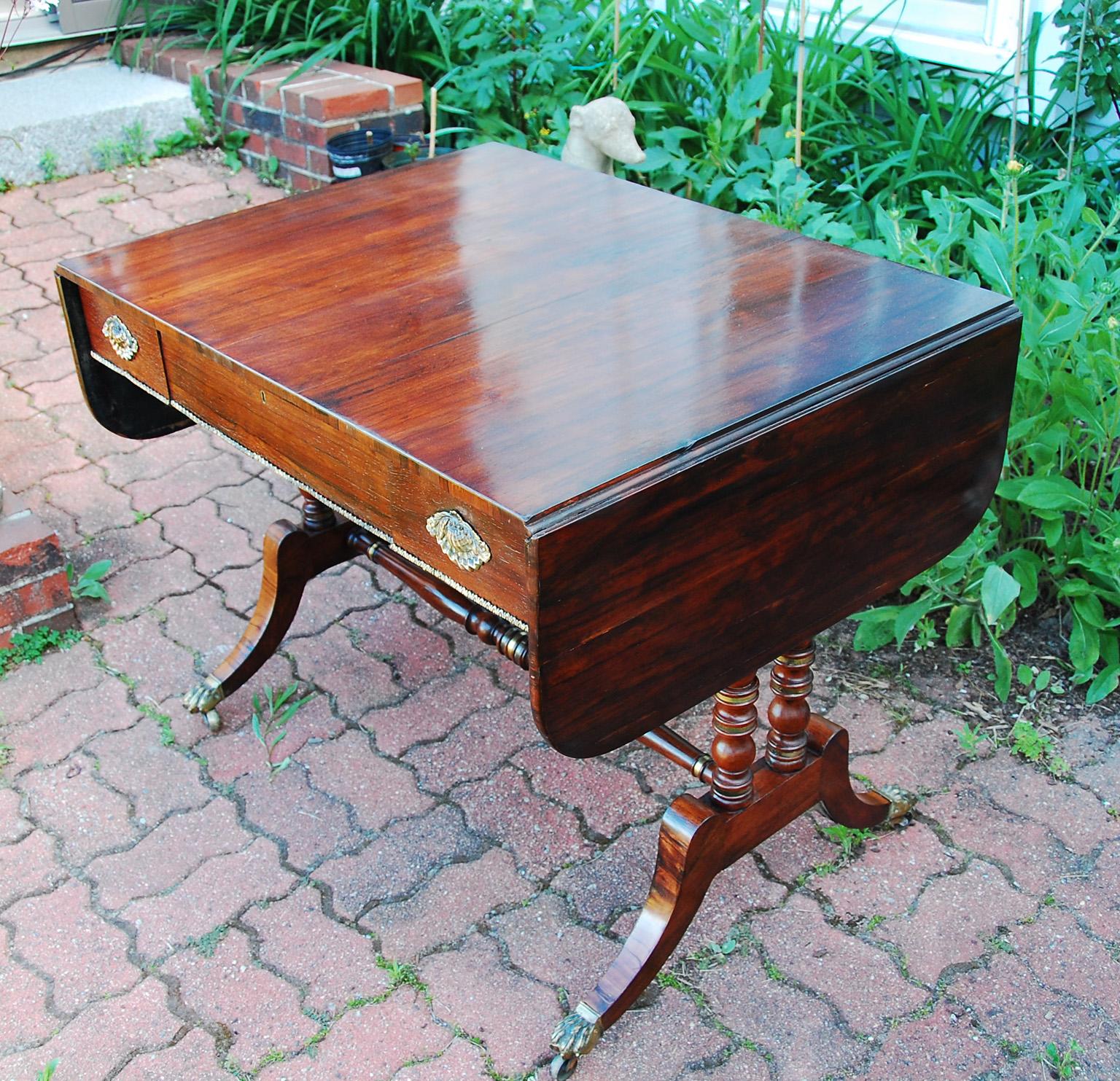 Table de canapé en bois de rose du milieu du XIXe siècle, avec des accents en laiton sur les tournures et la frise des tiroirs, poignées originales en forme de coquille en laiton.  Cette table est estampillée par le fabricant Edwards and Roberts. 